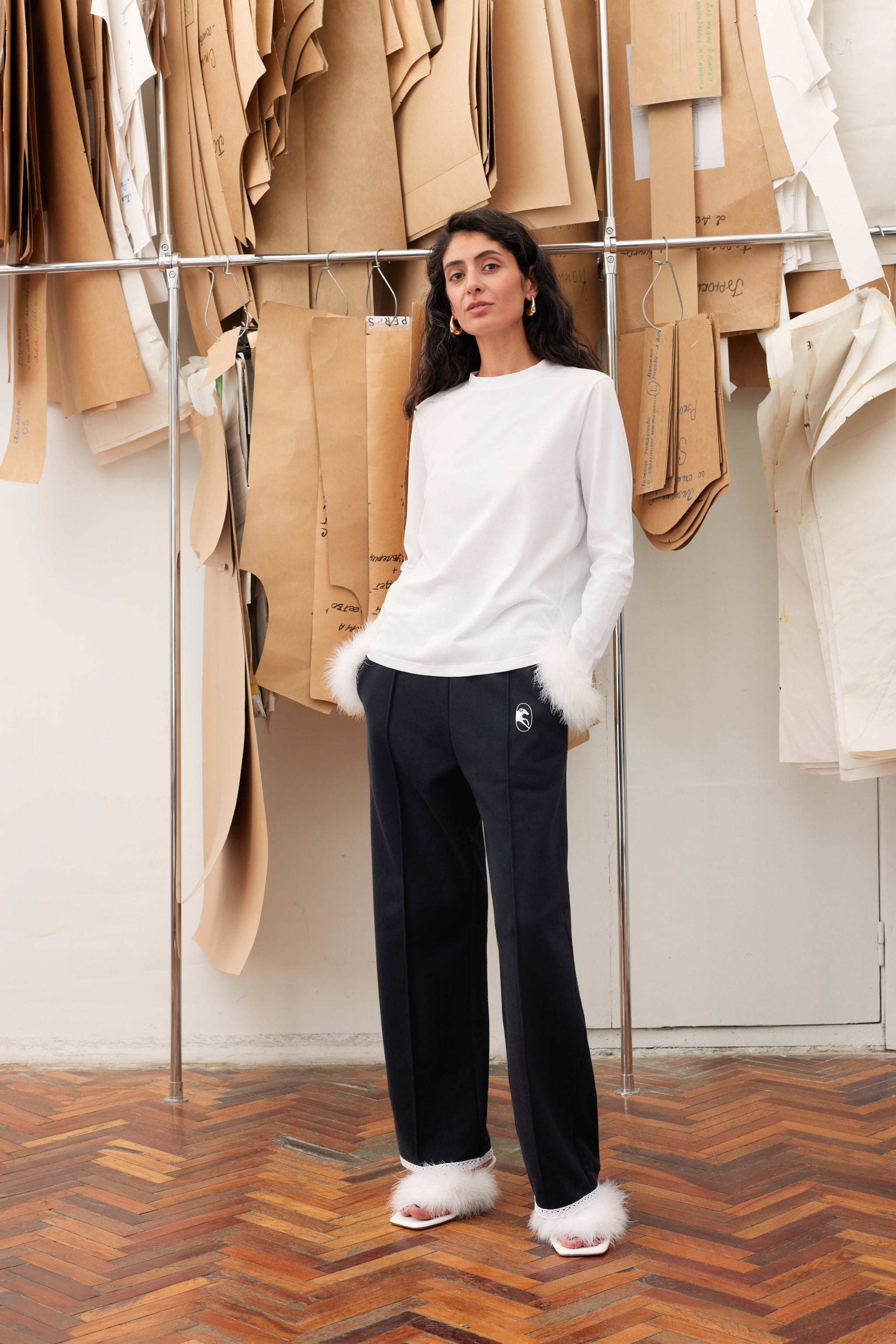 woman-wearing-white-long-sleeve-t-shirt-with-white-detachable-feather-cuffs-and-black-pants-with-hands-in-pockets