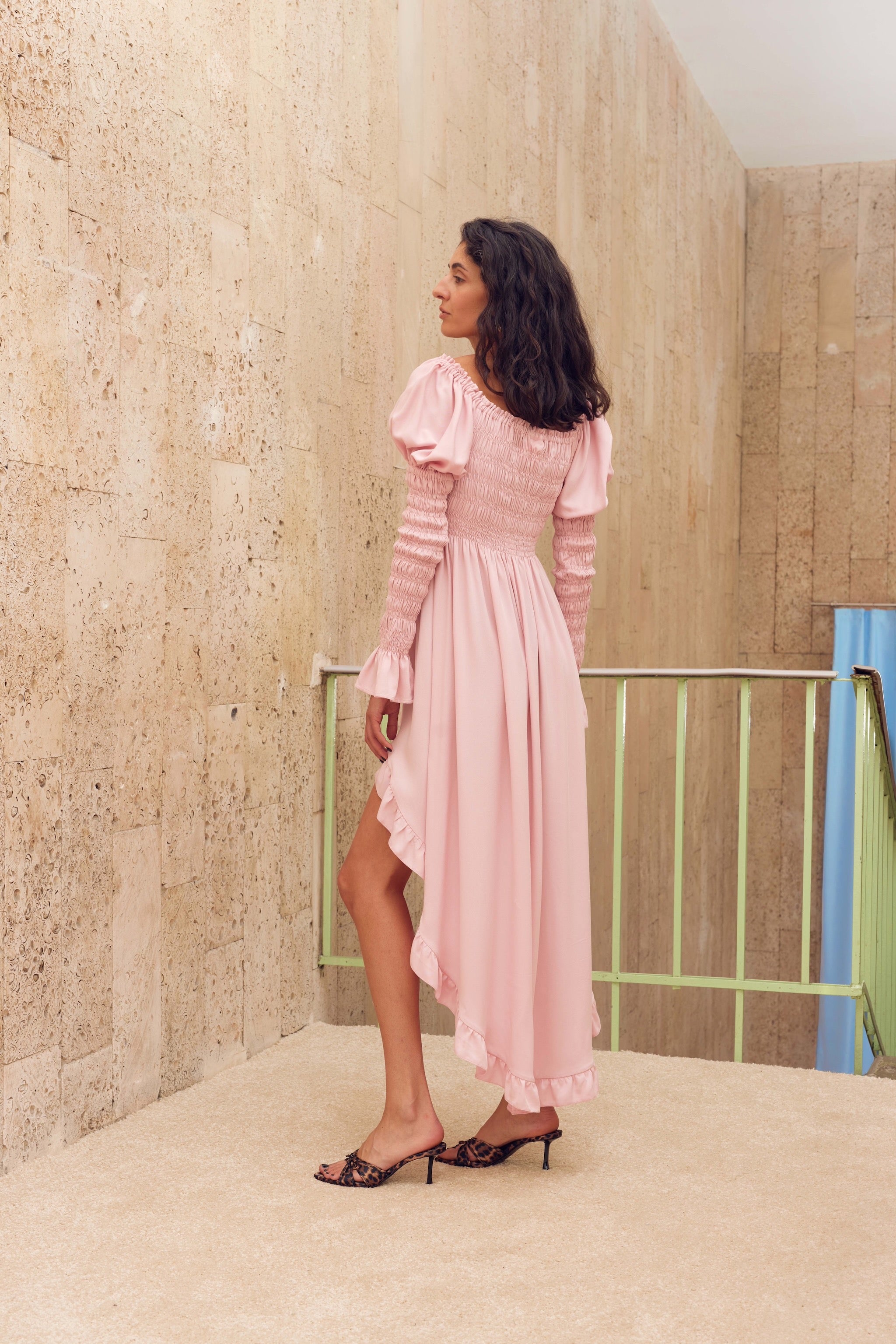 woman-standing-in-pink-long-sleeved-shirred-dress-with-side-slit