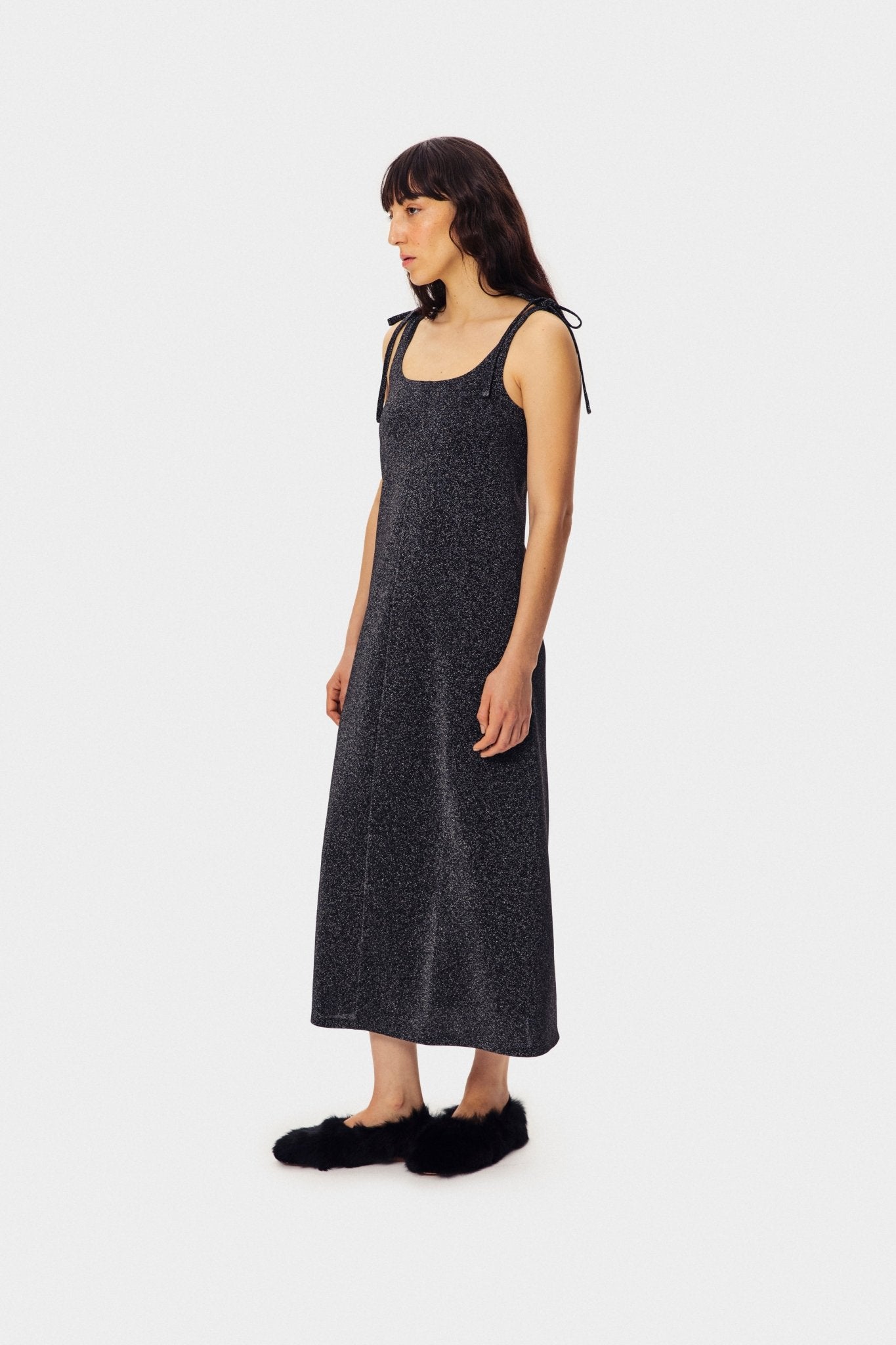 Woman wearing the black, scoop neckline, Lurex Slip Dress with black slippers.