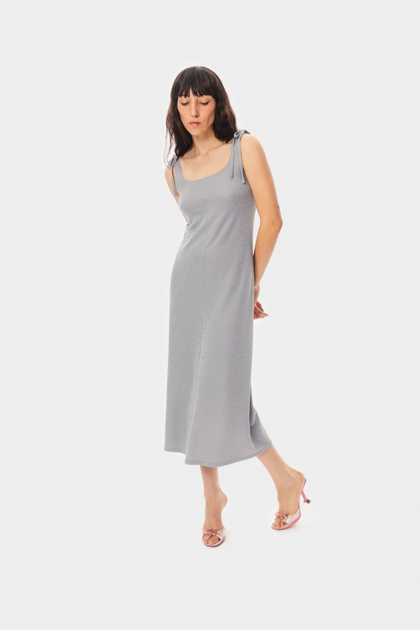 Woman wearing the Kylie Lurex Slip Dress in Silver and high heeled shoes.