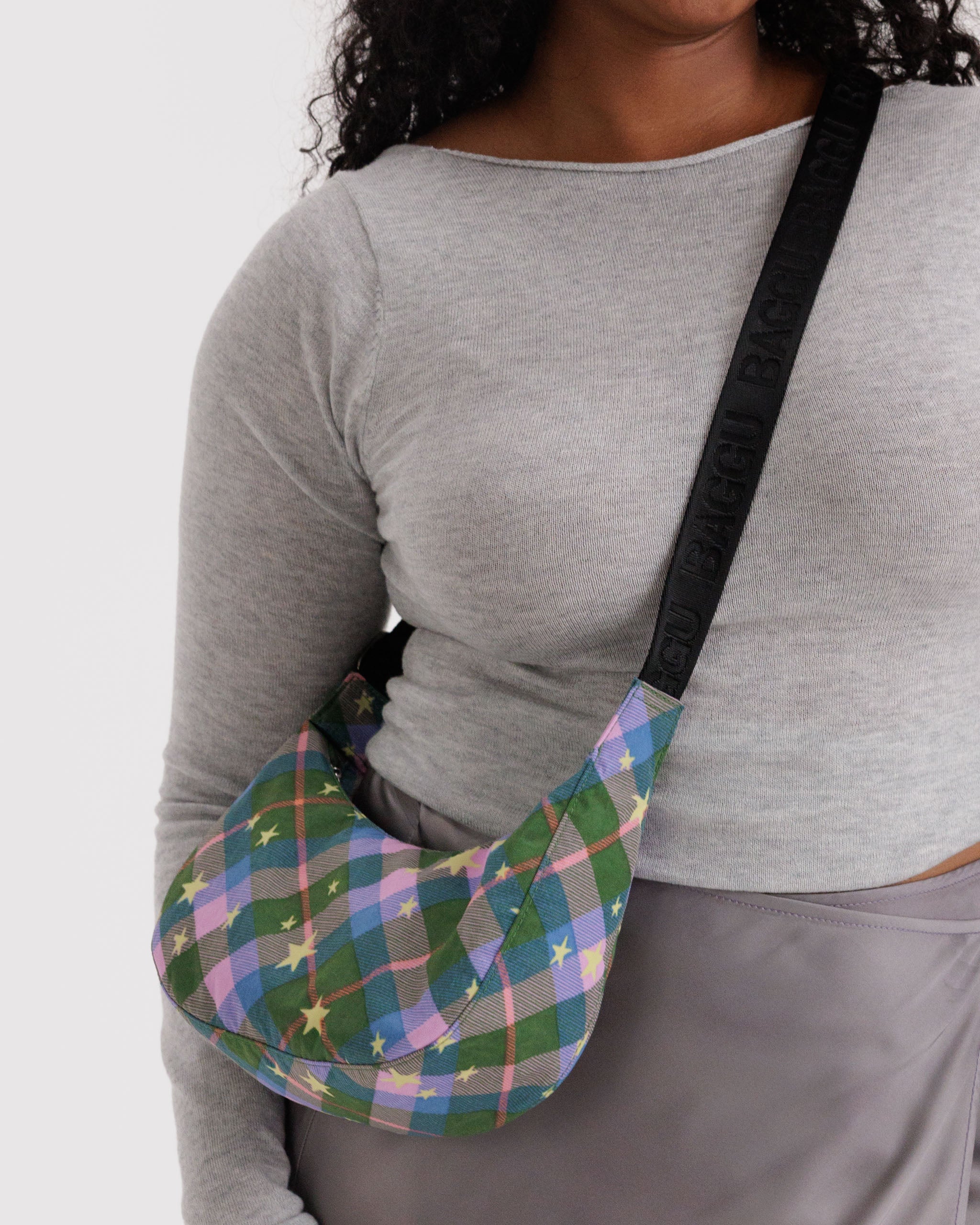 Person wearing a colorful green plaid with stars bag over their shoulder.
