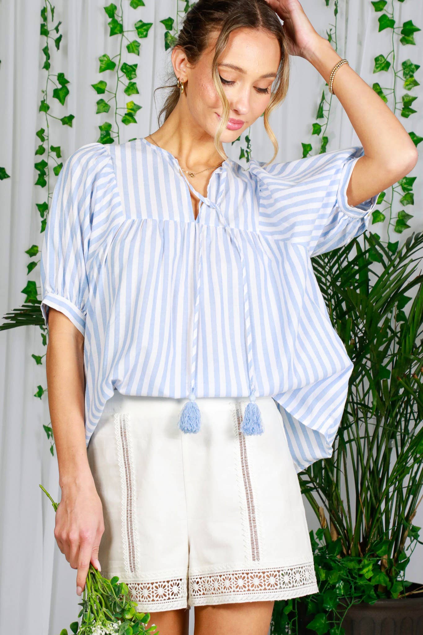 woman-wearing-Tie-Neck-Tassel-Trim-Short-Puff-Sleeve-Cotton-Top-and-shorts-touching-hair