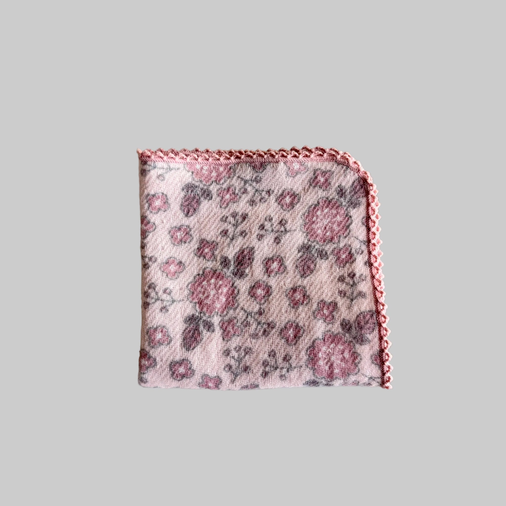 A folded pink with darker pink flowers print and delicate pink crotchet edge face cloth.