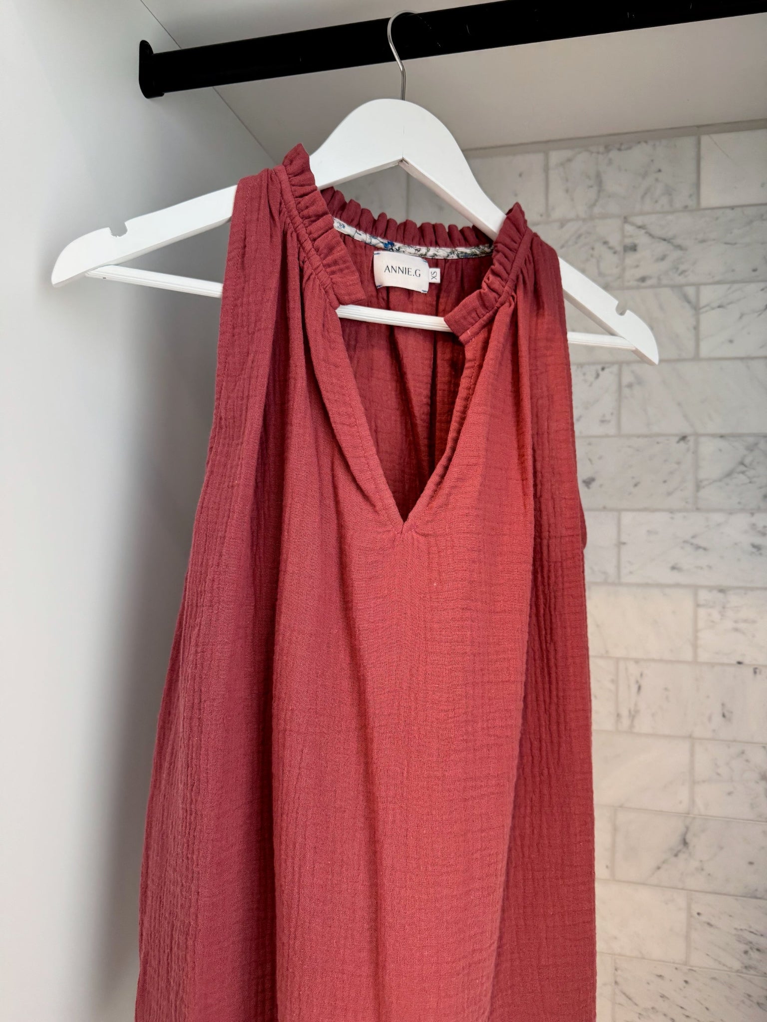 Maroon sleeveless top on a white hanger.