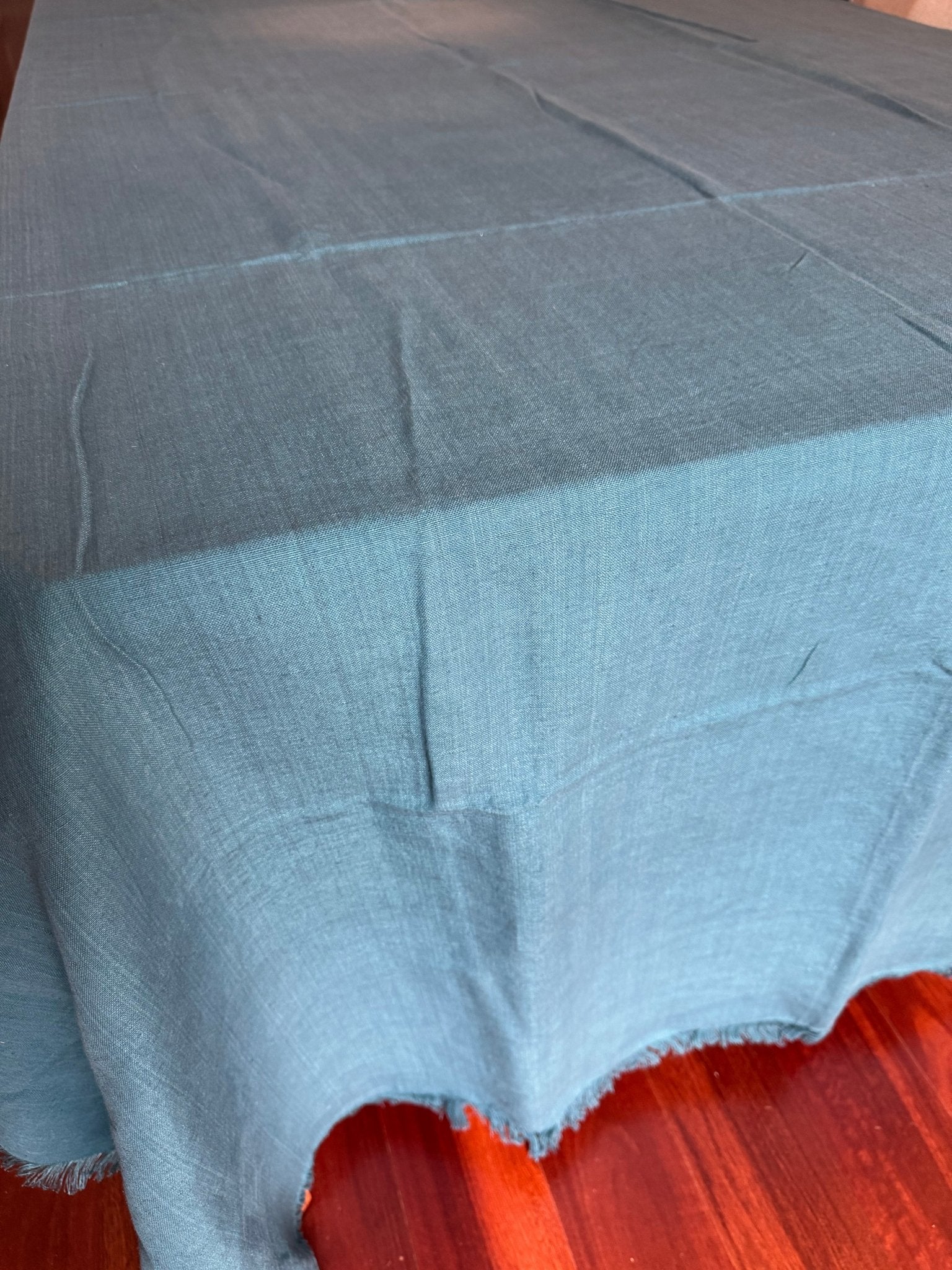 Close-up of teal tablelcoth with fringe edge on a dining table