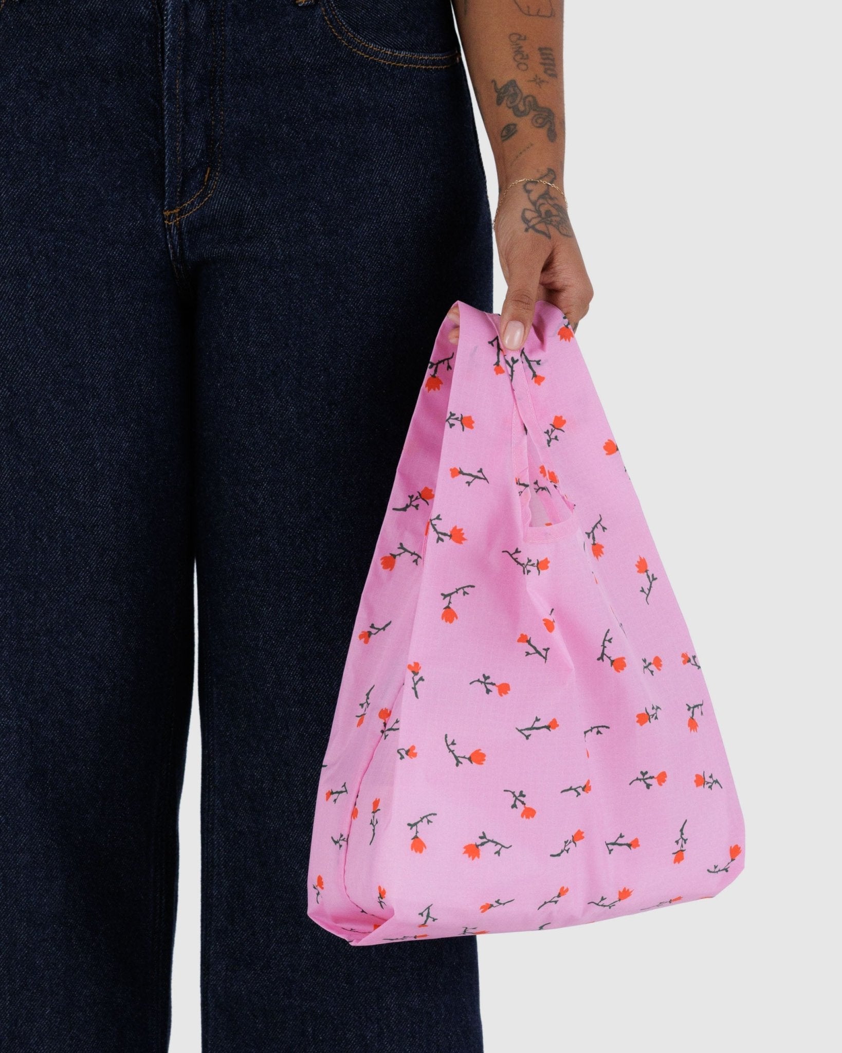 Person holding a pink baby baggu reusable bag with wildflower pattern