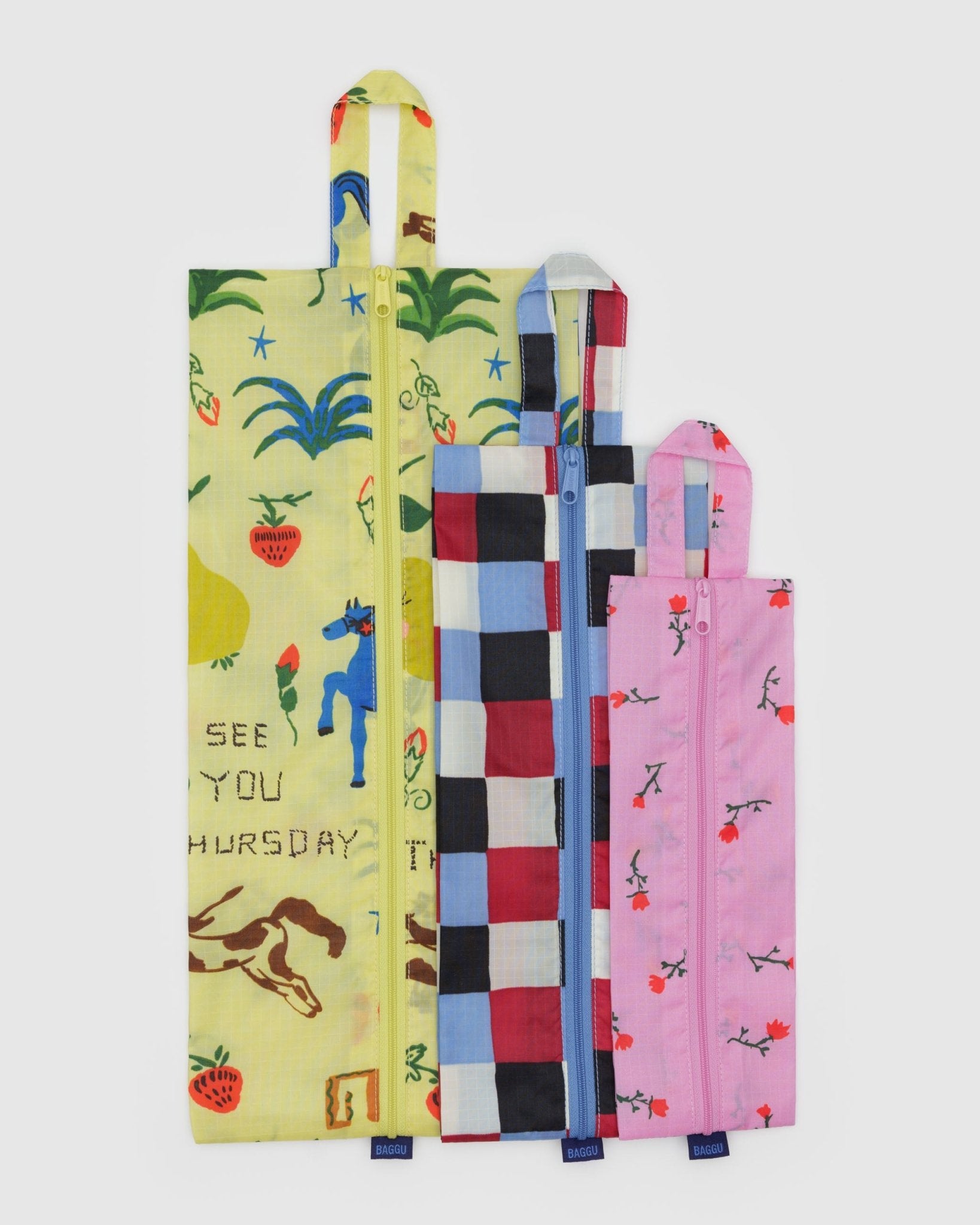 Three different sized, colourful print bags in yellow, pink and blue with different patterns and hanging loop at the top