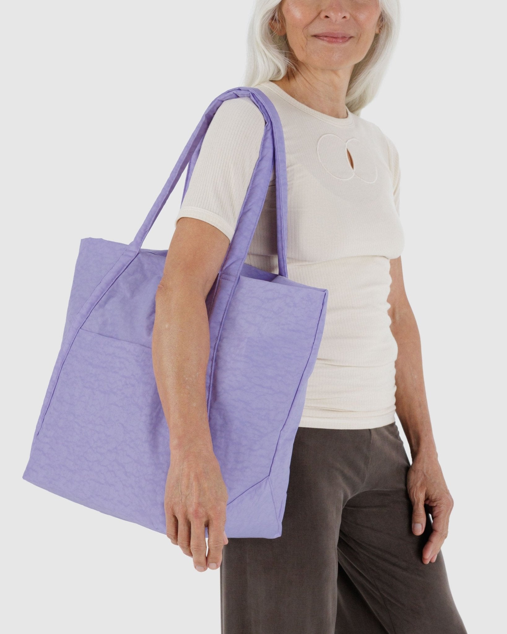 Person holding a purple tote shoulder bag with outside pocket and zip top