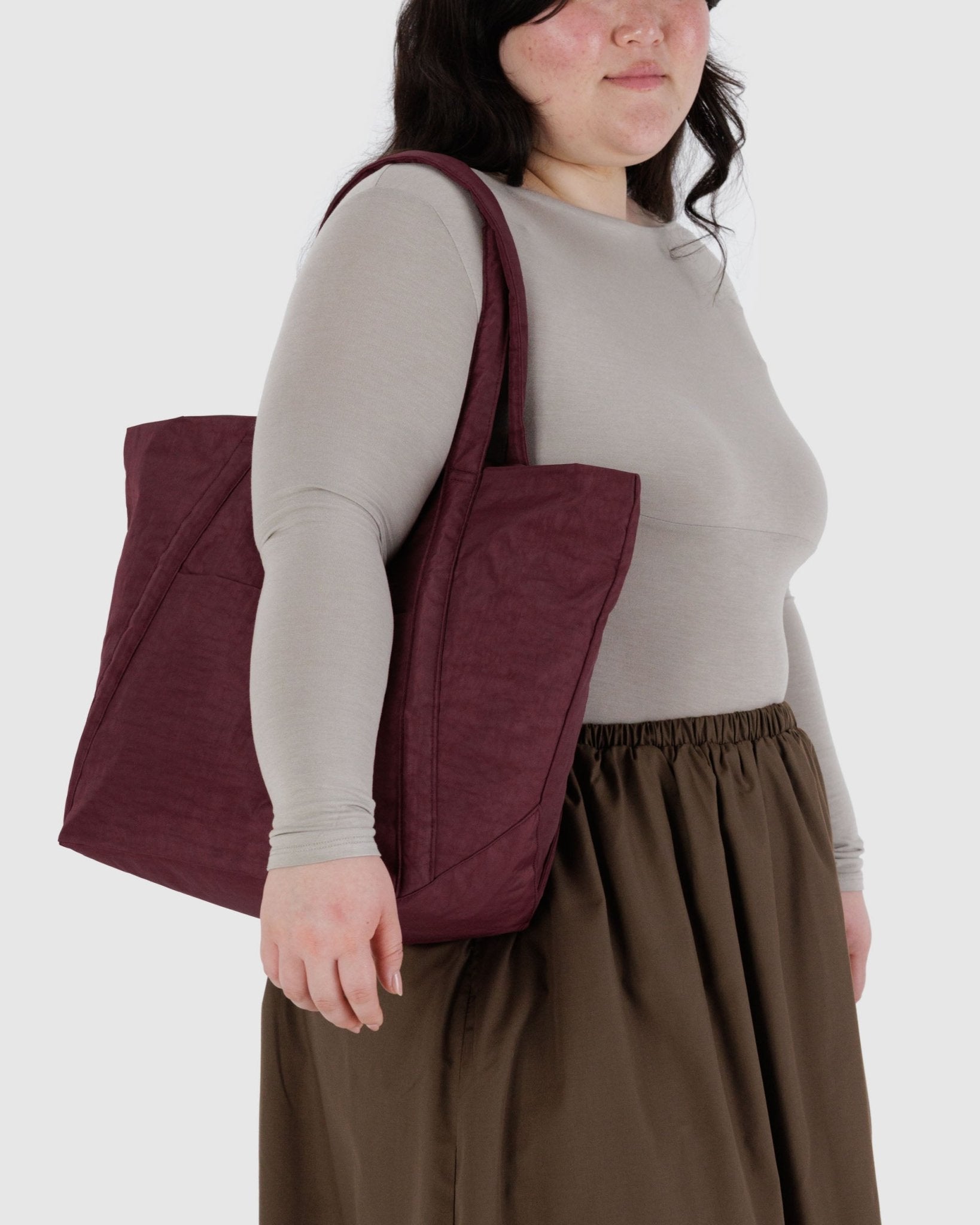 Person wearing a maroon tote bag over one shoulder