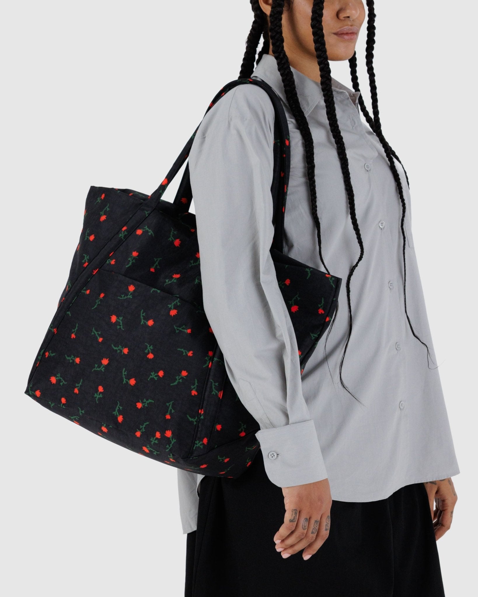 Person wearing a black tote bag with red wildflowers patterns