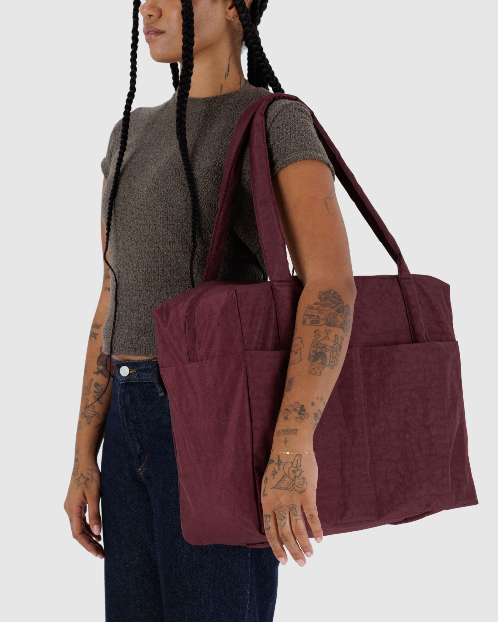 Person holding a large maroon duffle bag on shoulder