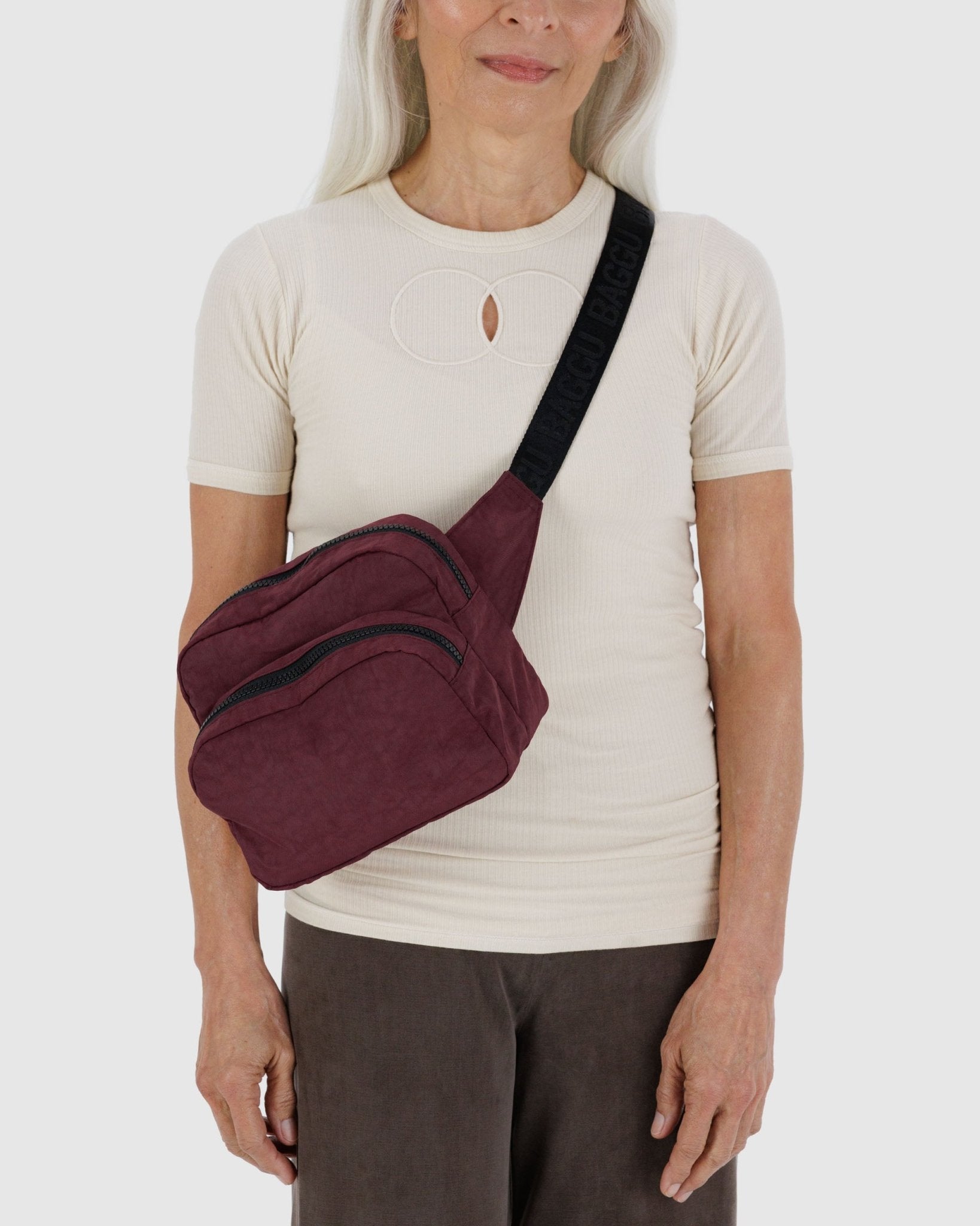 Person wearing a burgundy fanny pack crossbody