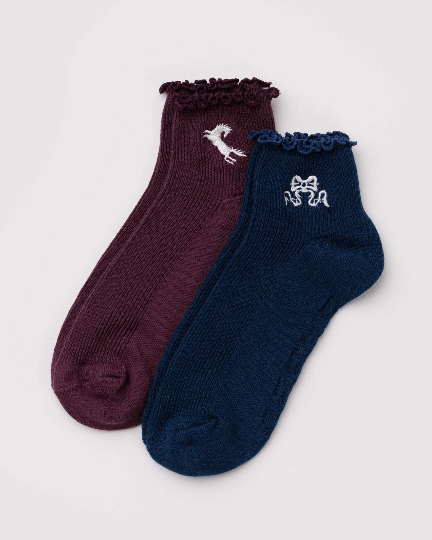 Two pairs of socks with decorative ruffles, one burgandy/maroon with horse embroidery and one navy with bow embroidery