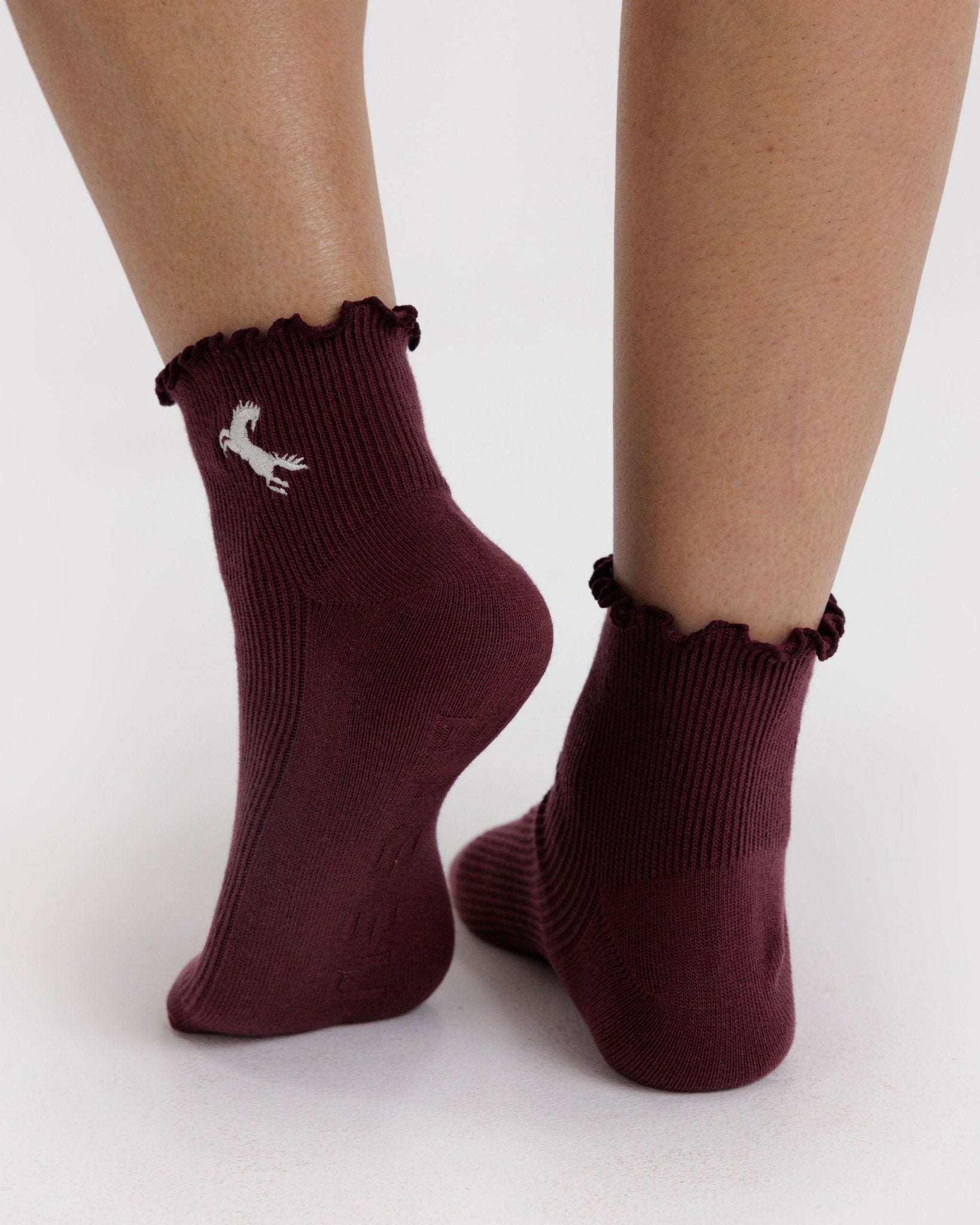 Burgundy/Maroon socks with ruffled top and white horse embroidery worn by a person
