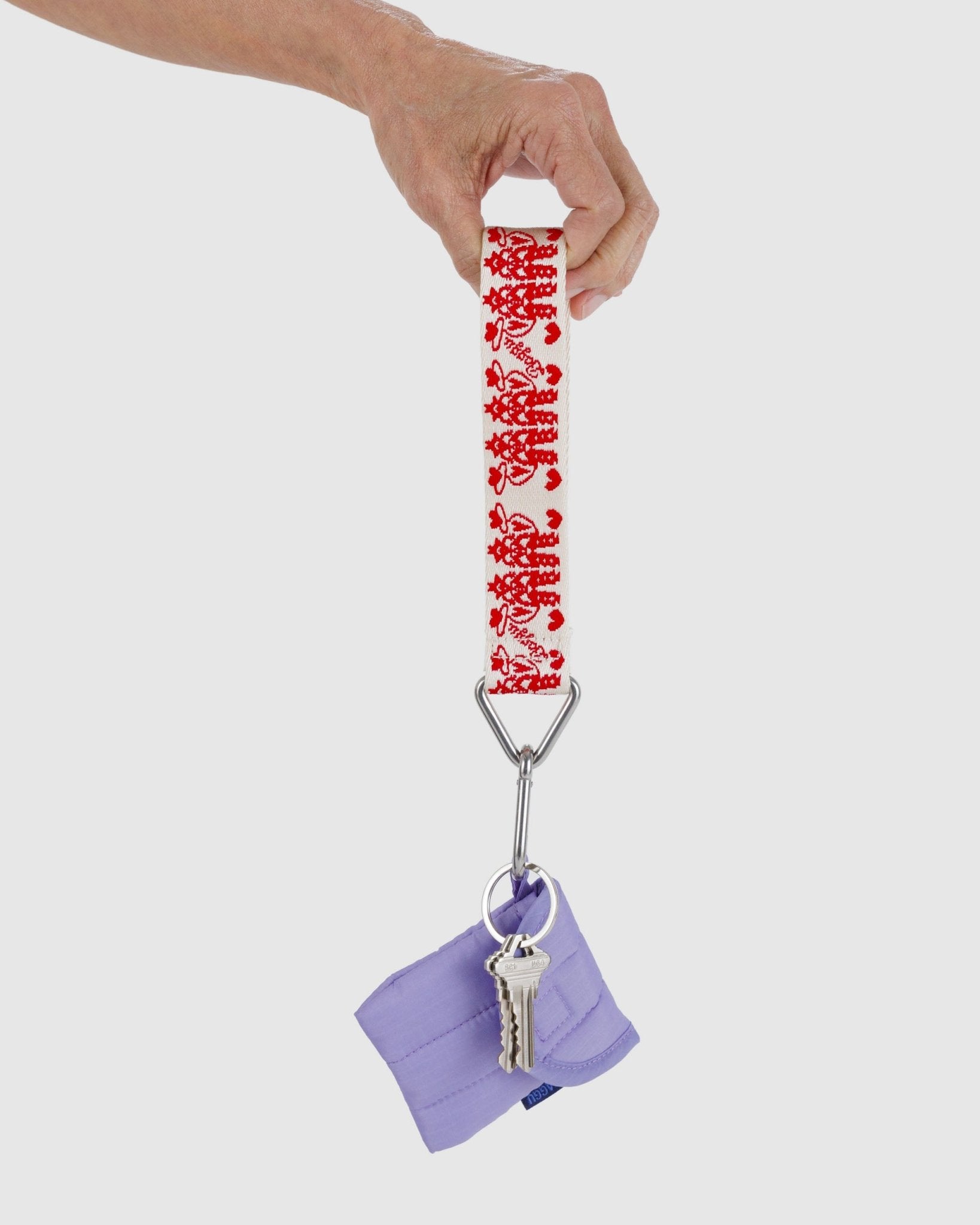 Hand holding a keychain with a red cowgirl pattern and purple puffy earbuds case pouch