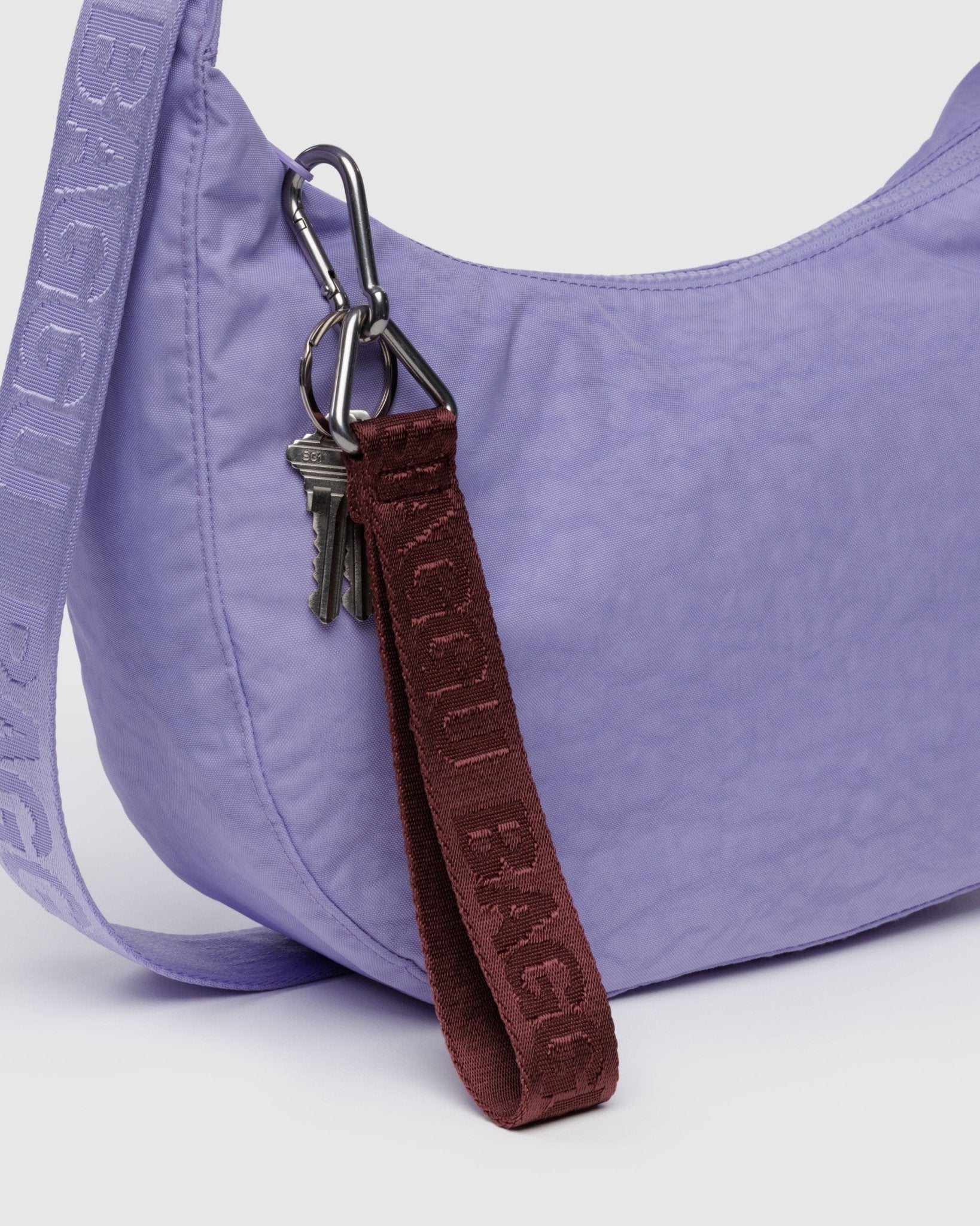 Purple crescent crossbody bag with a burgundy BAGGU branded keychain and keys attached to zip