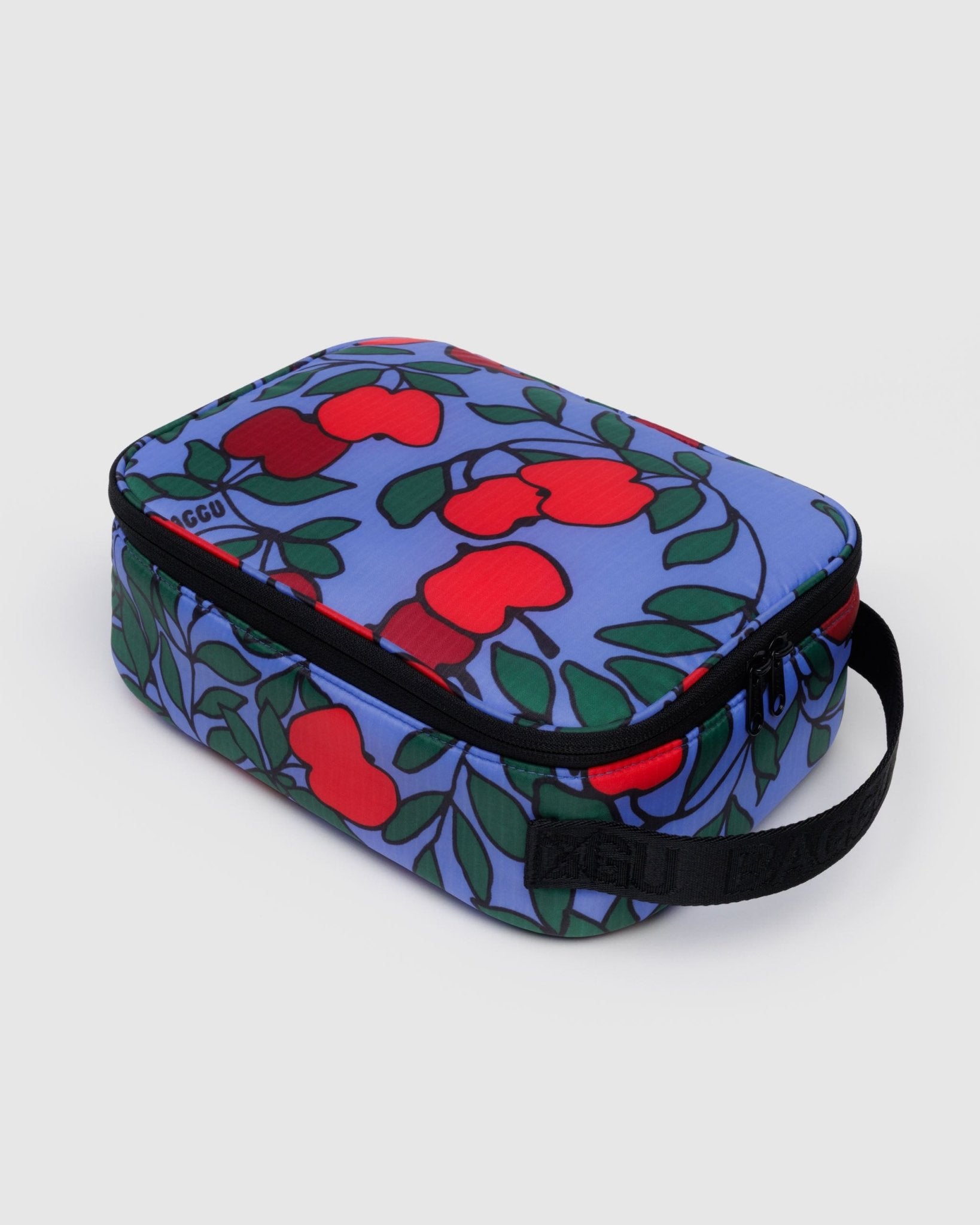 Rectangular lunch box with red apple pattern on a blue background with a zip closure and black carry handle