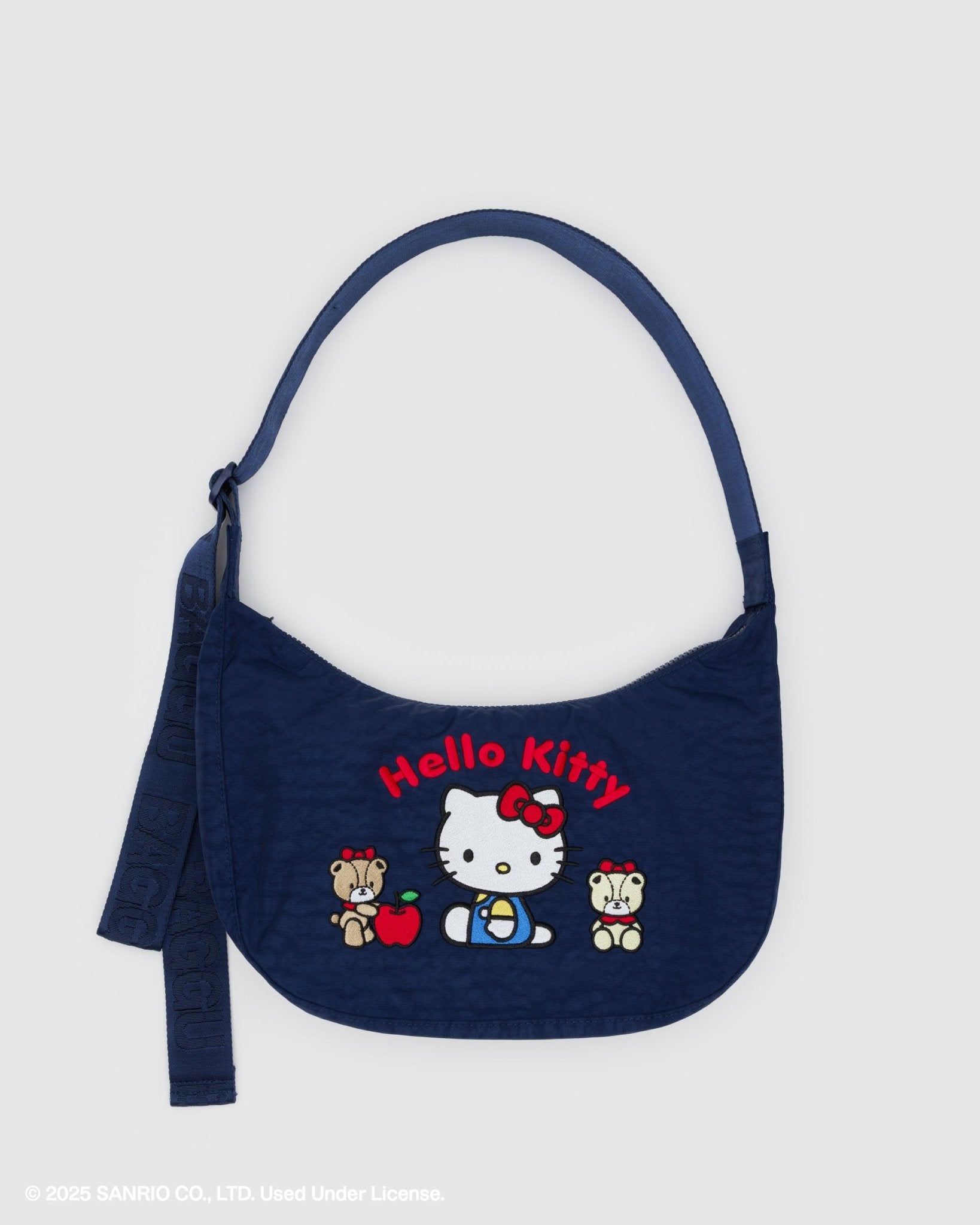 Navy blue crescent crossbody bag with embroidered red Hello Kitty words and design on front and adjustable shoulder strap