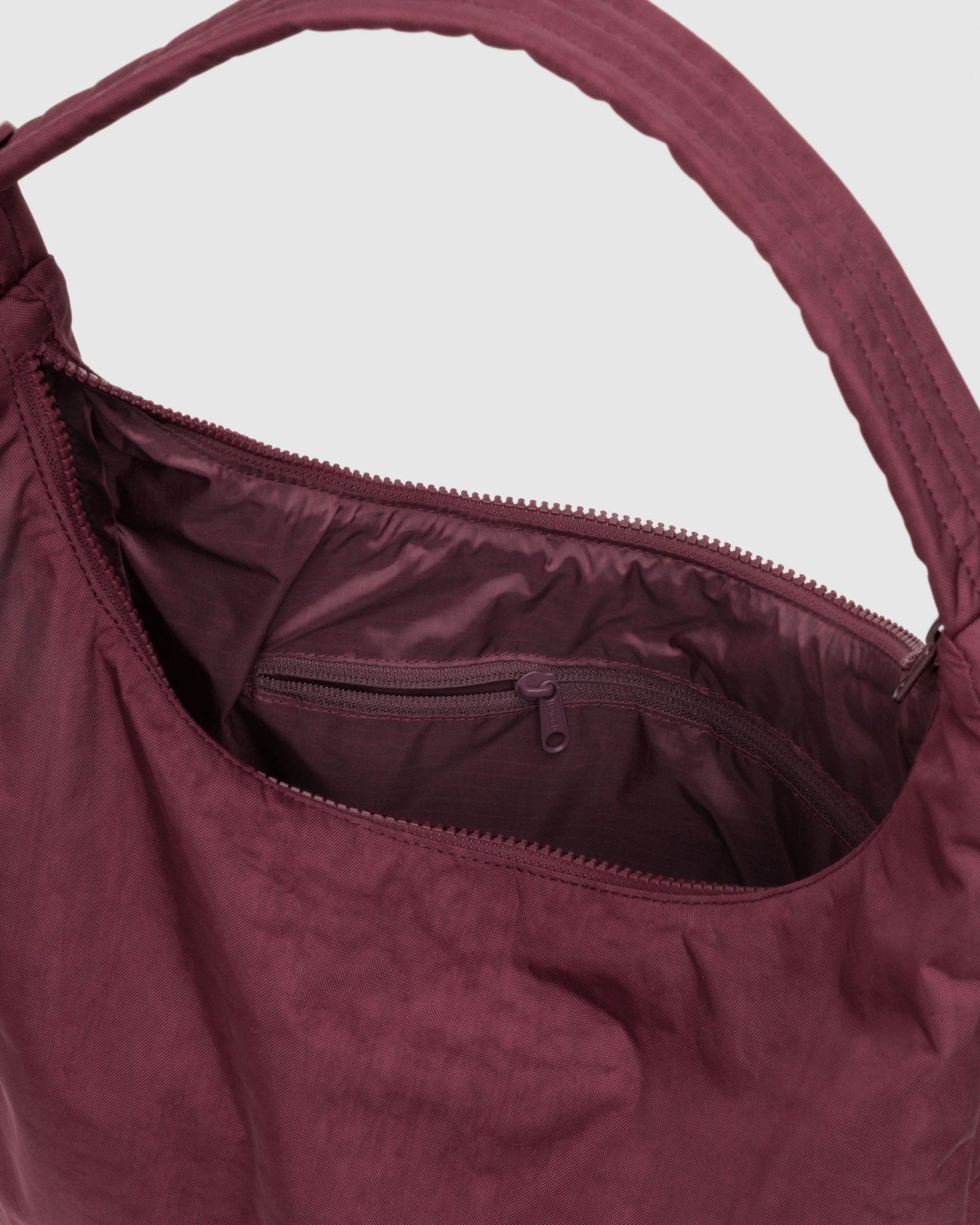 Maroon handbag with open zip top showing interior pocket.