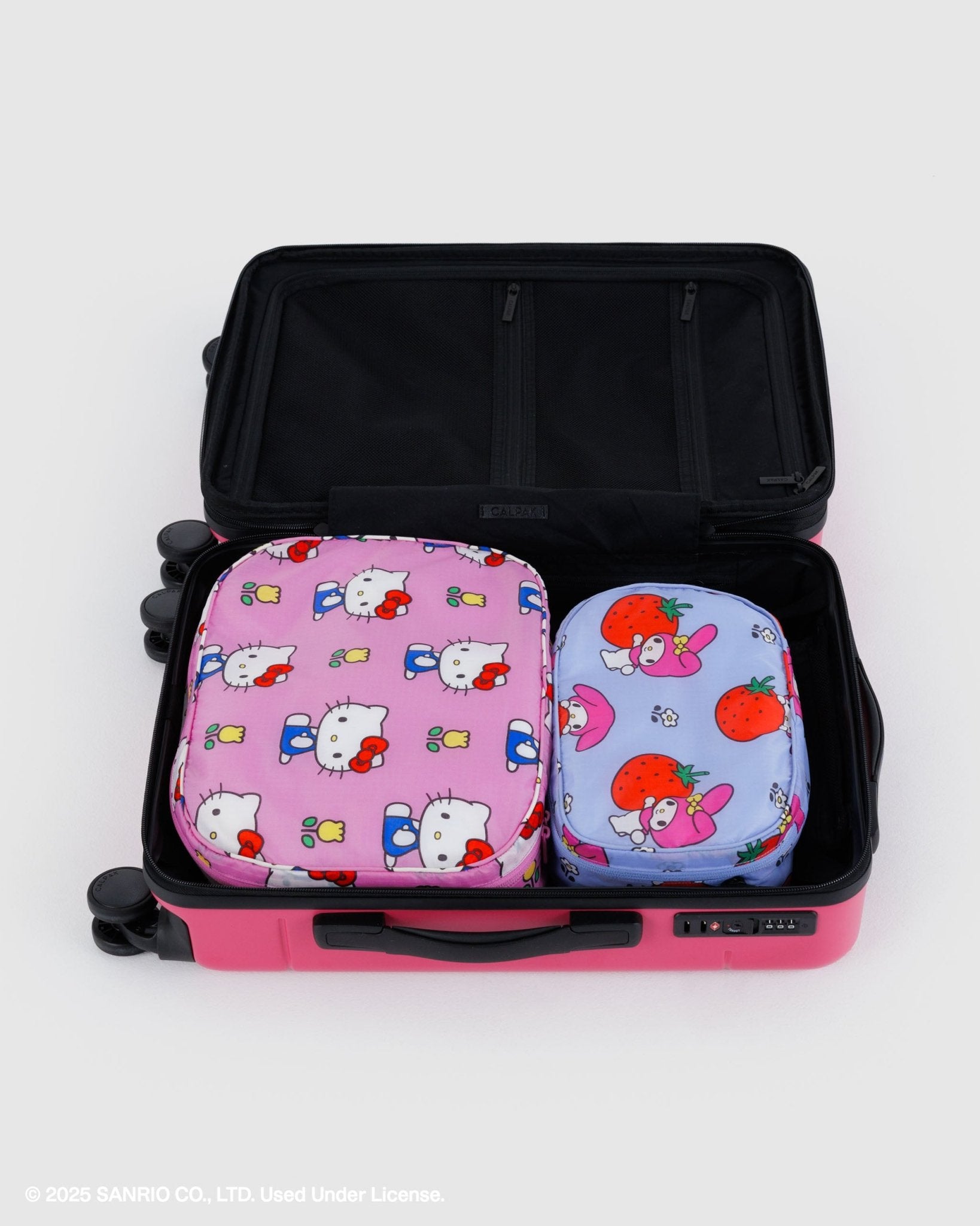 Two sized cartoon-themed pink and blue zipped packing cubes in an open suitcase