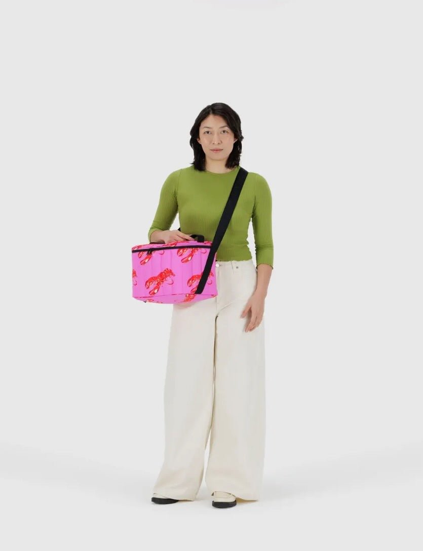 Woman holding a pink quilted bag with a red lobster pattern crossbody