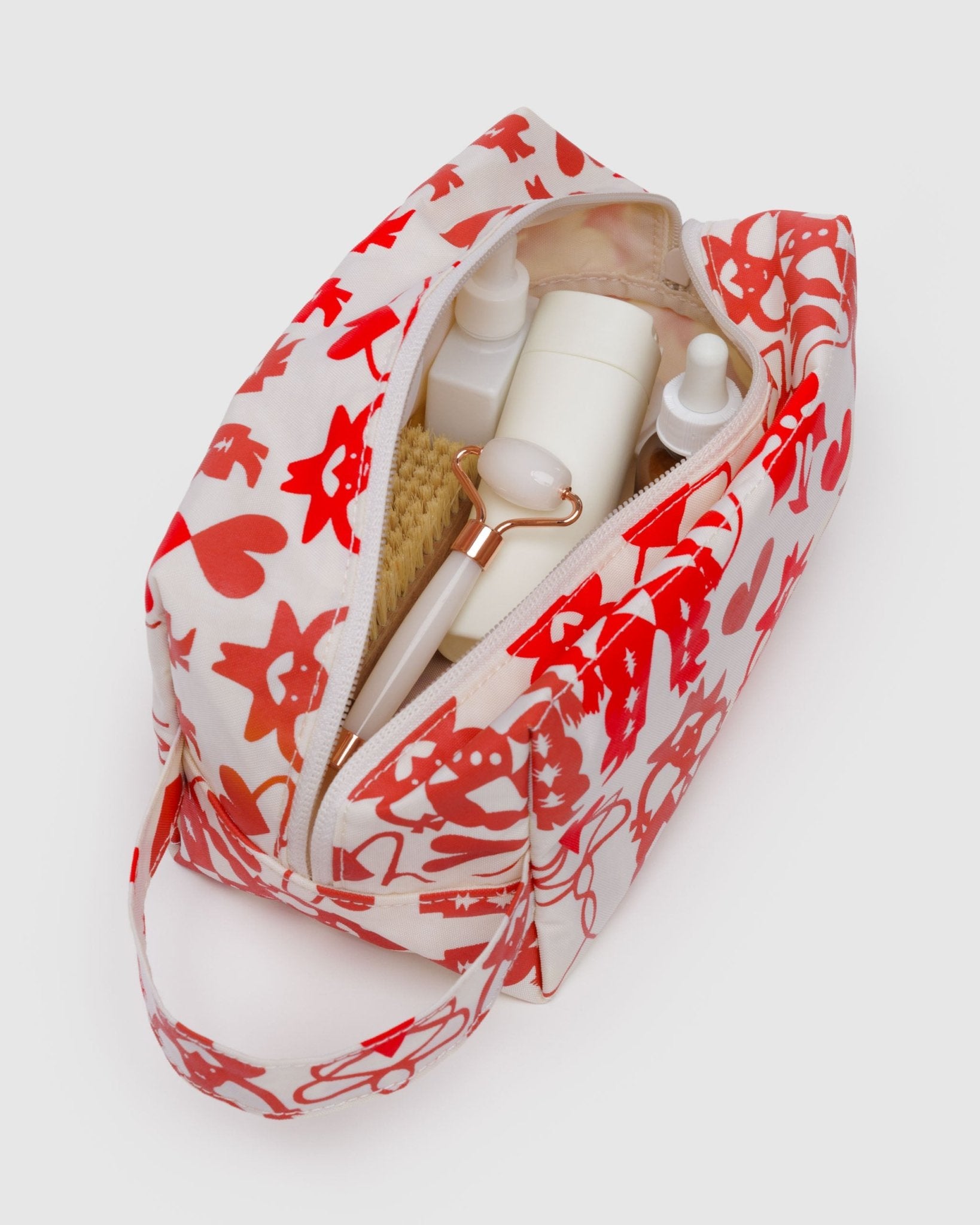 Makeup bag with red cowgirl pattern containing beauty products with zip open and carry handle.