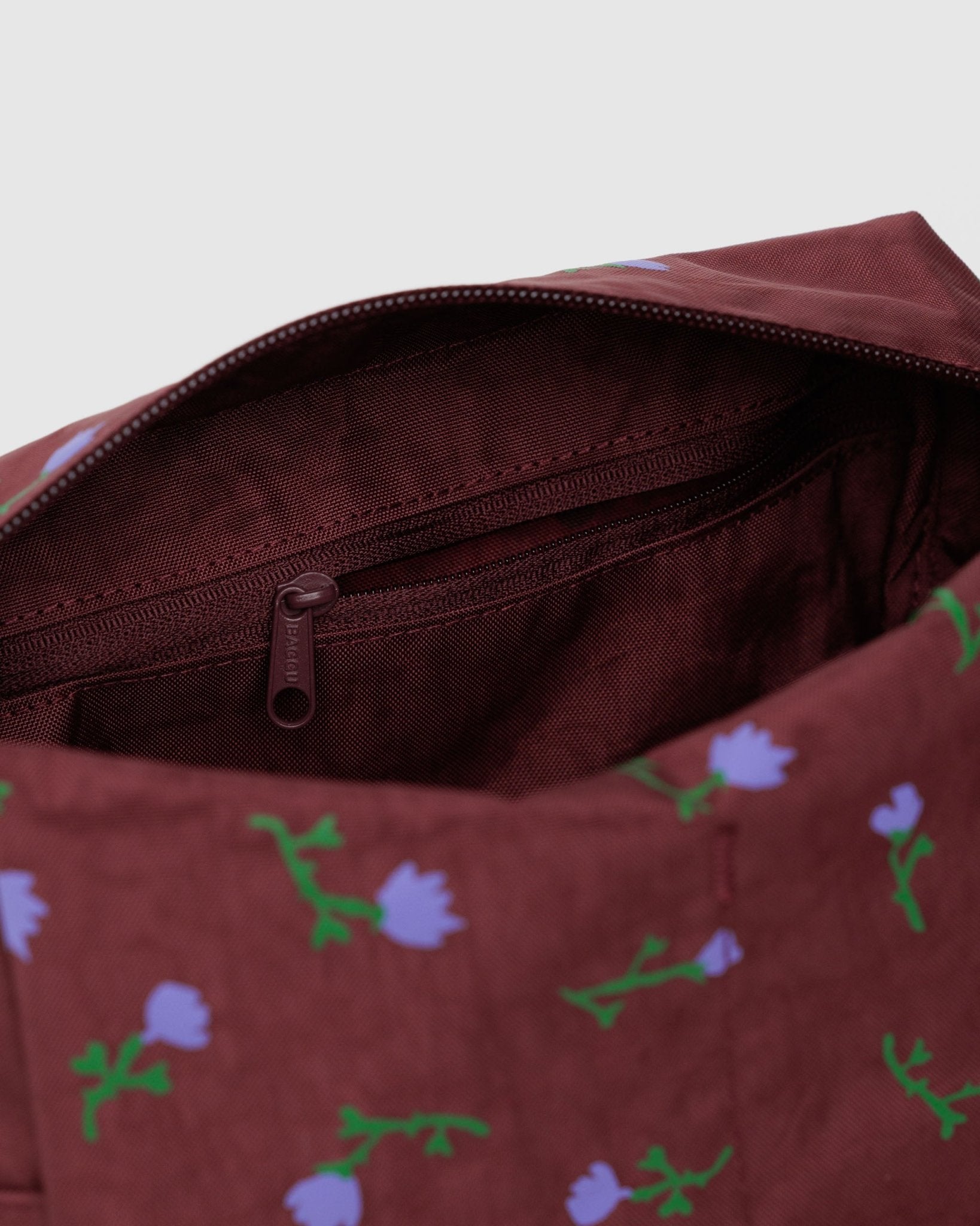 Burgundy toiletry bag with purple wildflower pattern and internal zip pocket and lining.