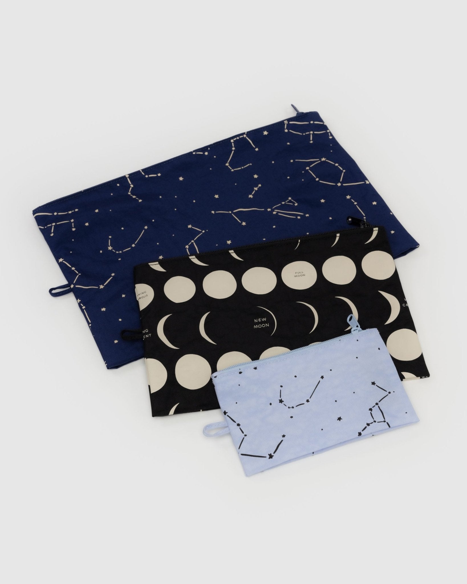 Three different sized pouches unfilled and lying flat in blue colours with stars and moon prints