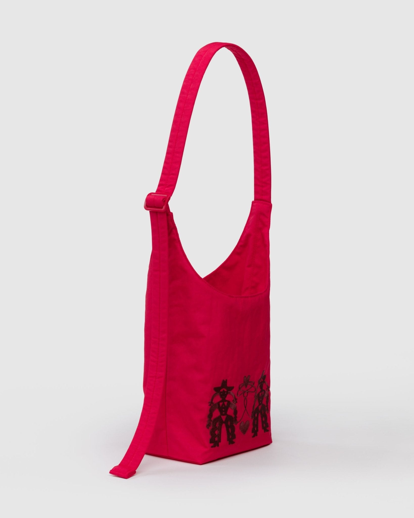 Side of red small sling bag with black cowgirl designs with adjustable strap