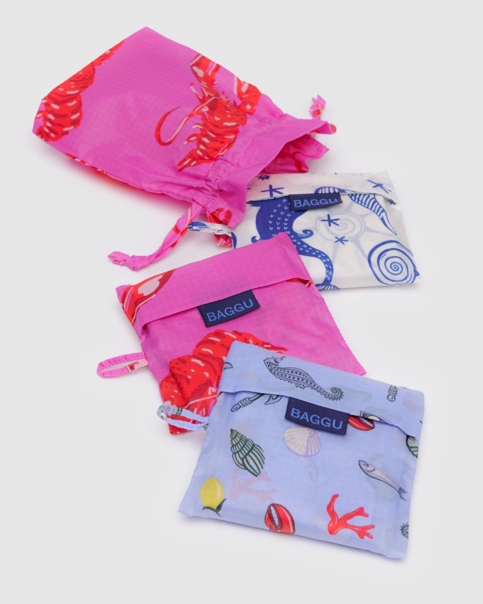 Set of 3 colourful reusable bags with 'BAGGU' branding in prints of mermaid, lobster and sea charms with pouch