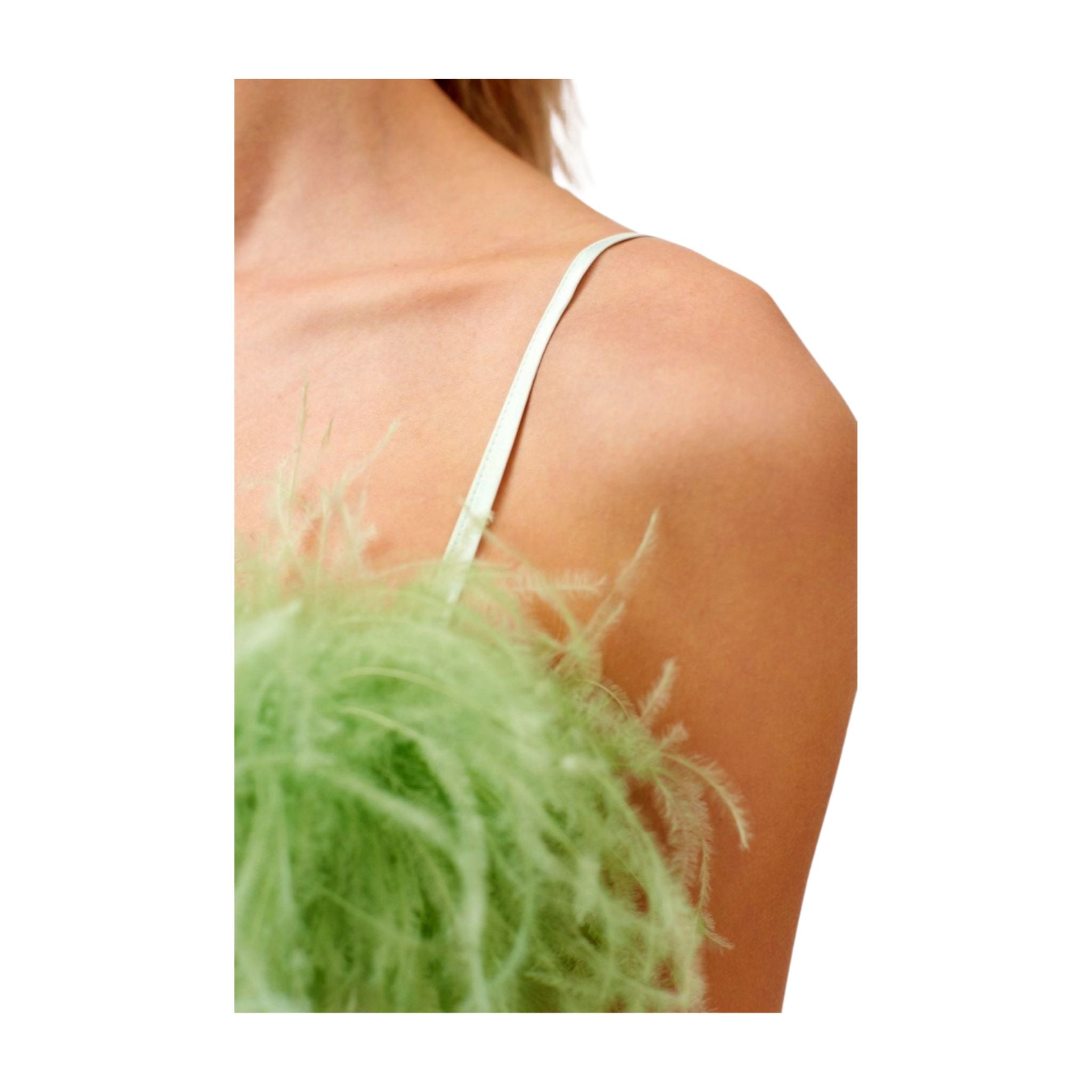 Close-up of a person wearing a mint dress with spaghetti strap top with a green feathers.