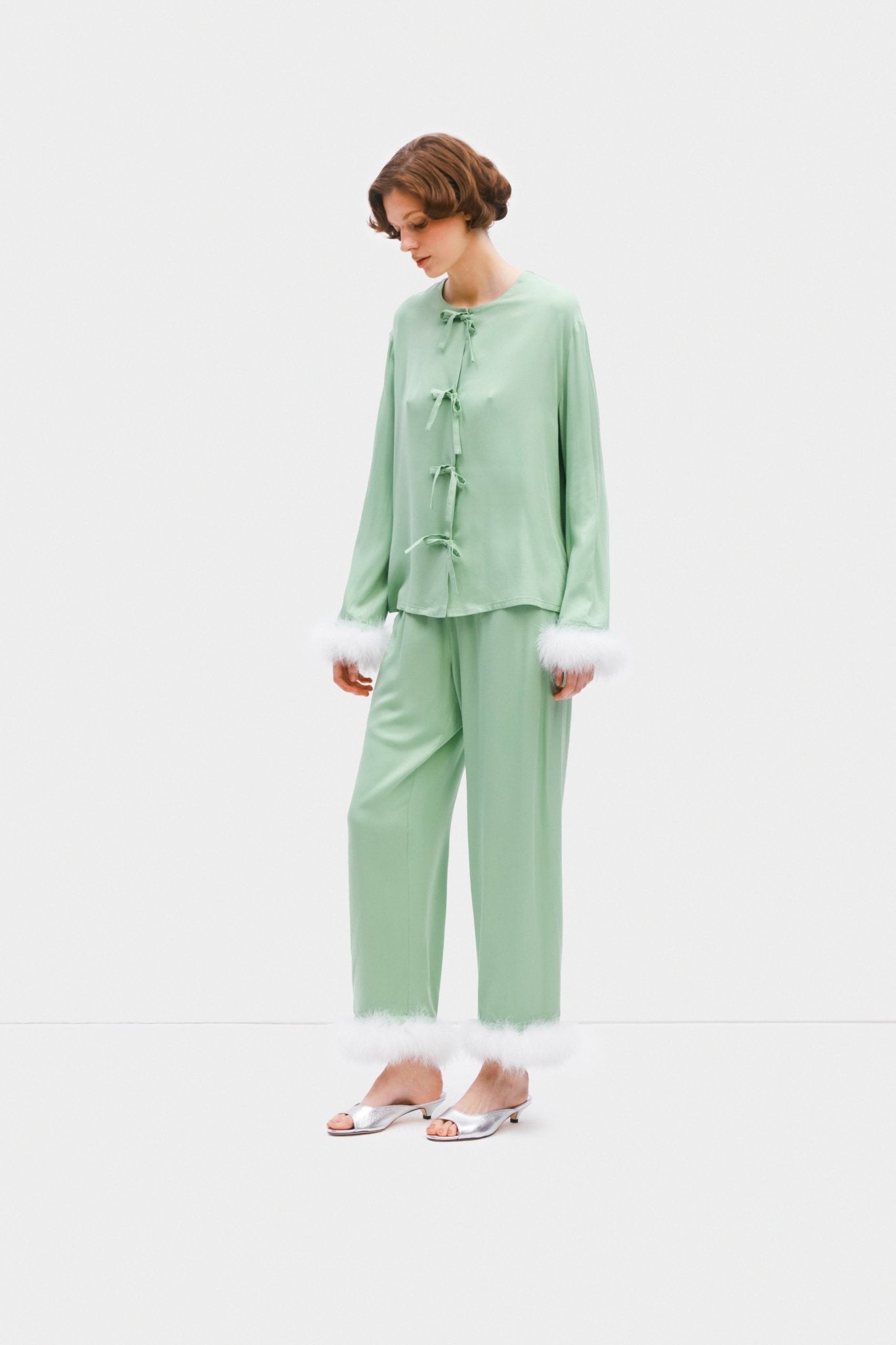 Side of woman wearing mint pyjama top with tie bows and pants with white feather cuffs - ANNIE.G