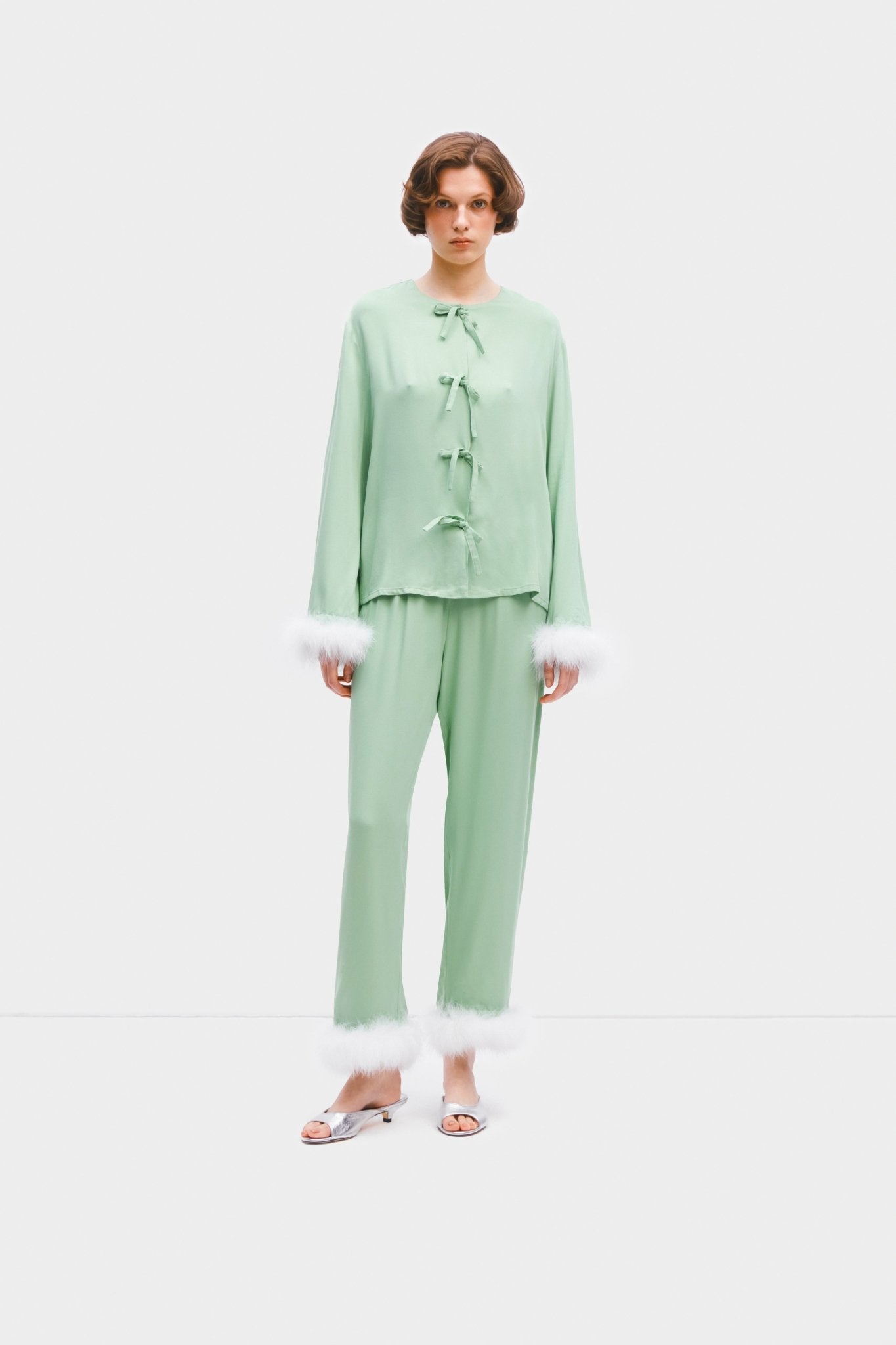 Woman wearing mint coloured pyjama top and pants set with detachable white feathers - ANNIE.G