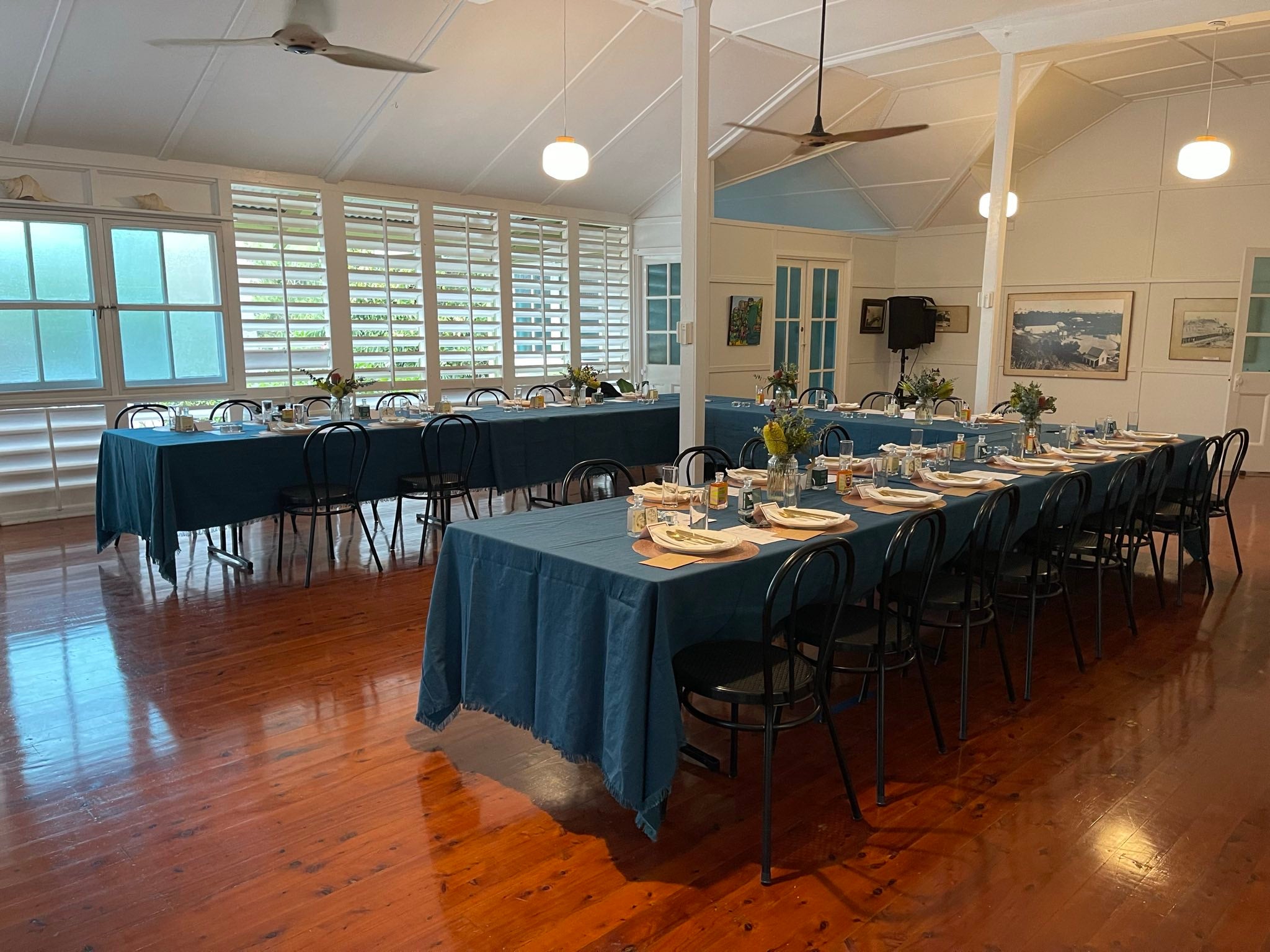 Long rectangular tables covered with teal tablecloth and white napkins set up for a meal at a wedding