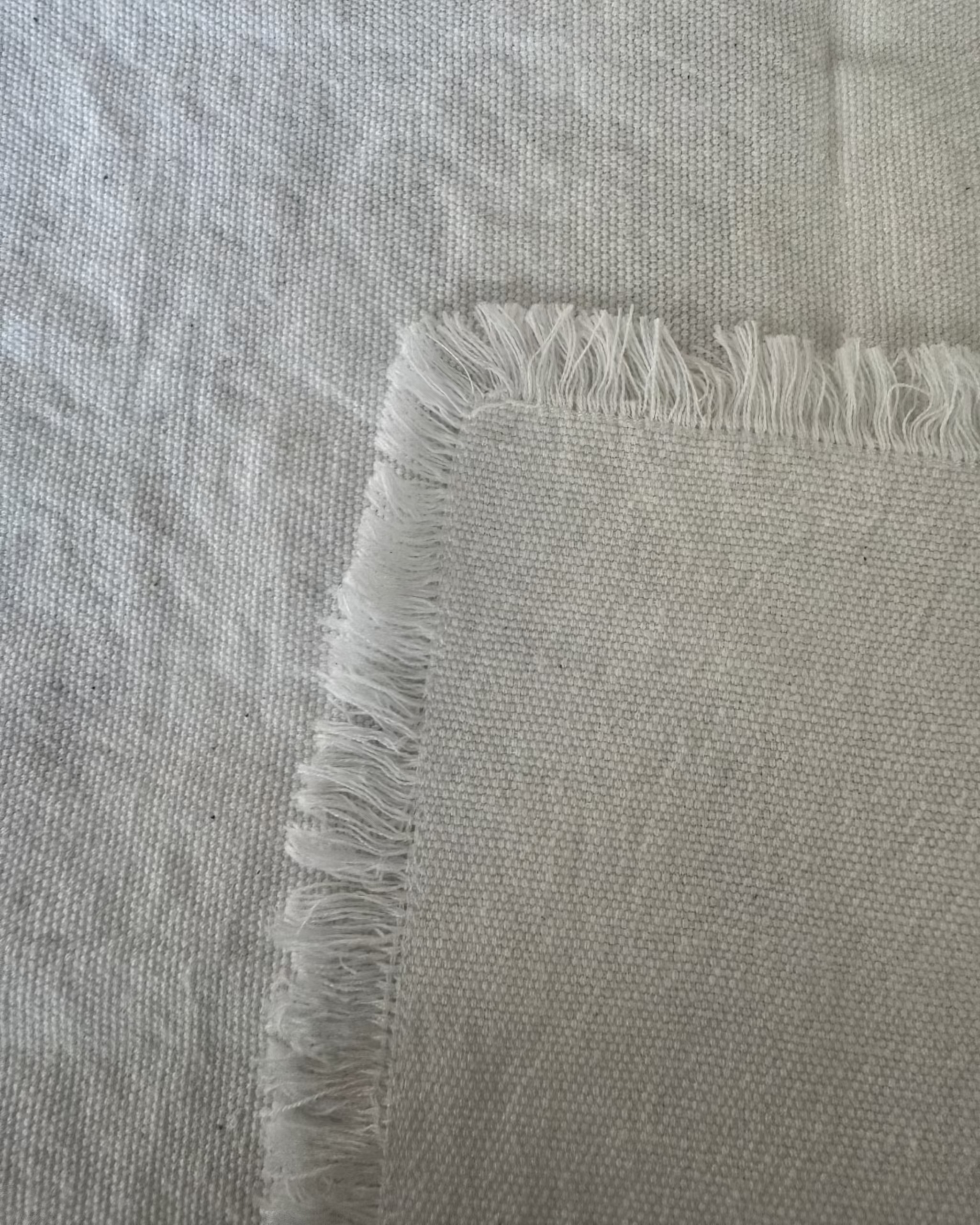 Close-up of a white cotton napkin with frayed edges