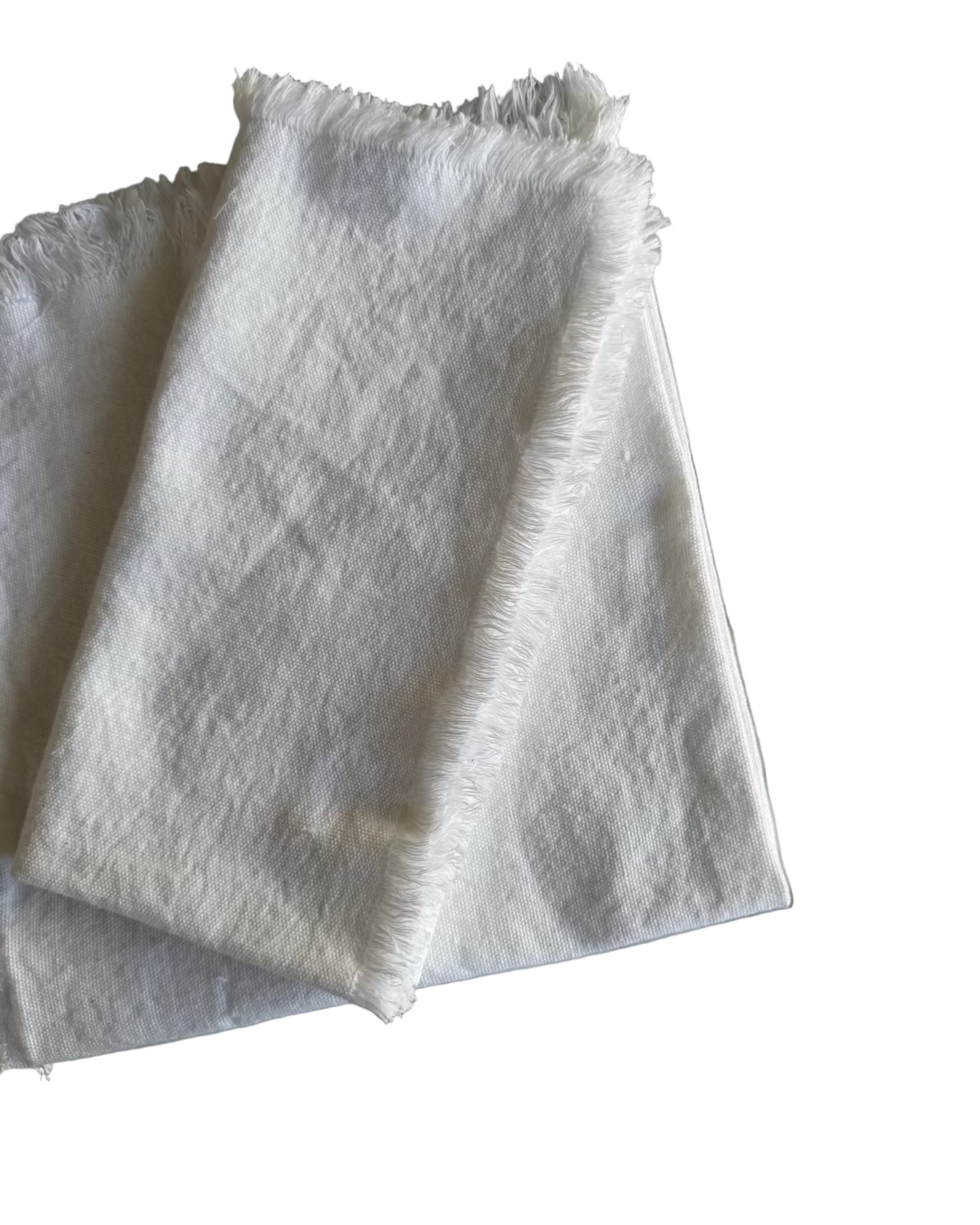 One white fabric napkin with a frayed edge folded on top of another white napkin