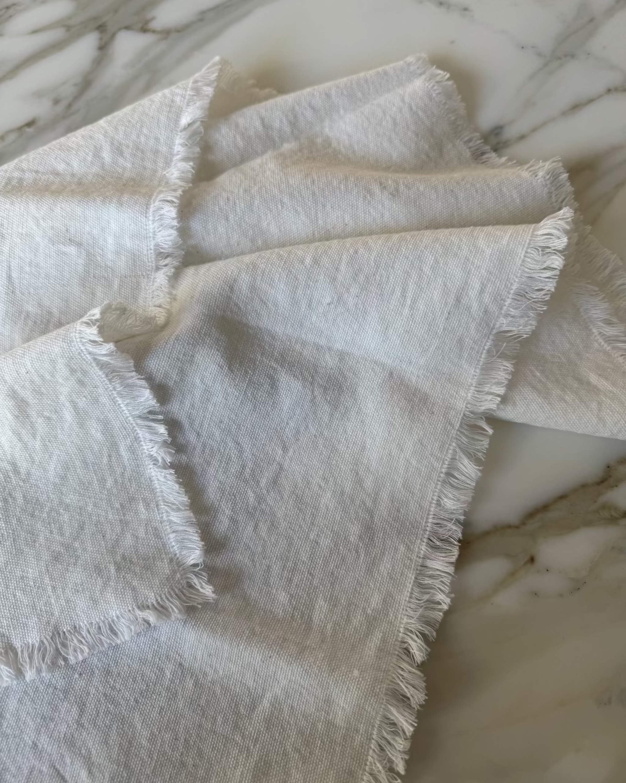 White cotton napkin with frayed edges on a marble surface