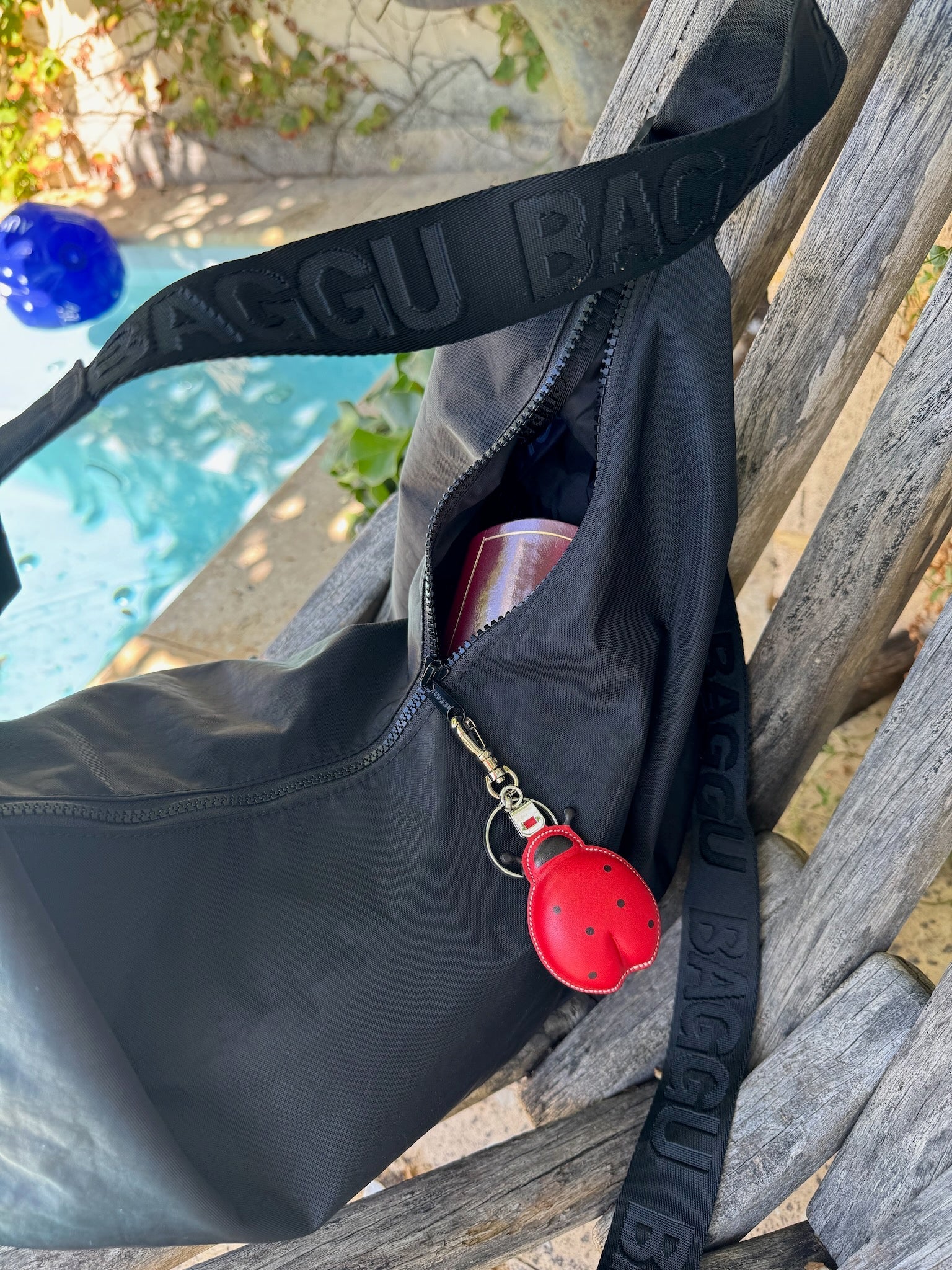 Red leather Ladybug Keychain Bag Charm attached to zip of black bag on a seat - ANNIE.G