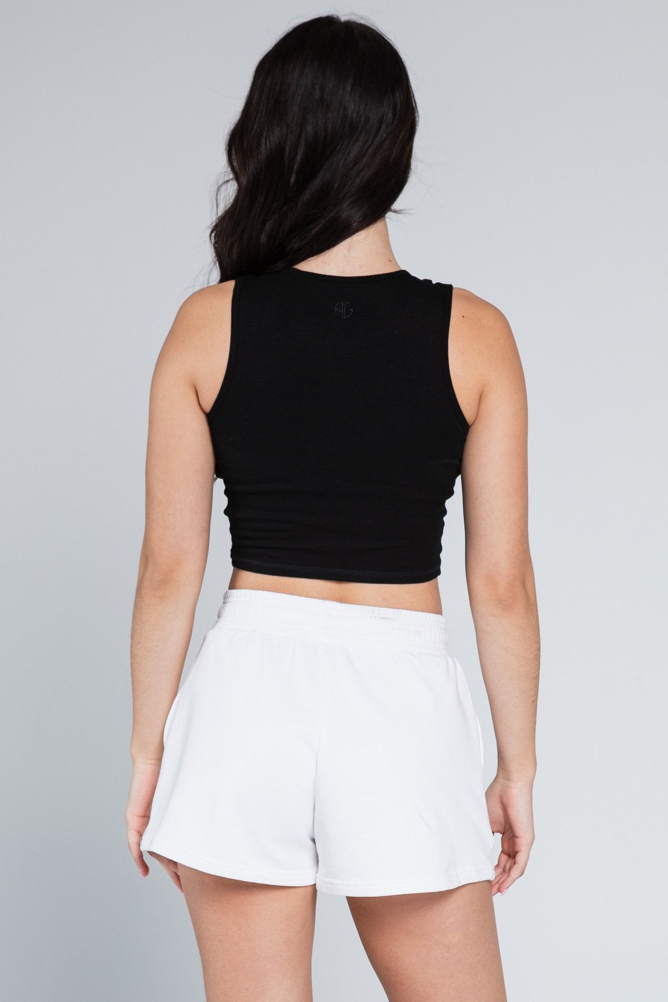 Back of a woman wearing white loungewer Sweat Shorts with elastic waist and black crop top - ANNIE.G