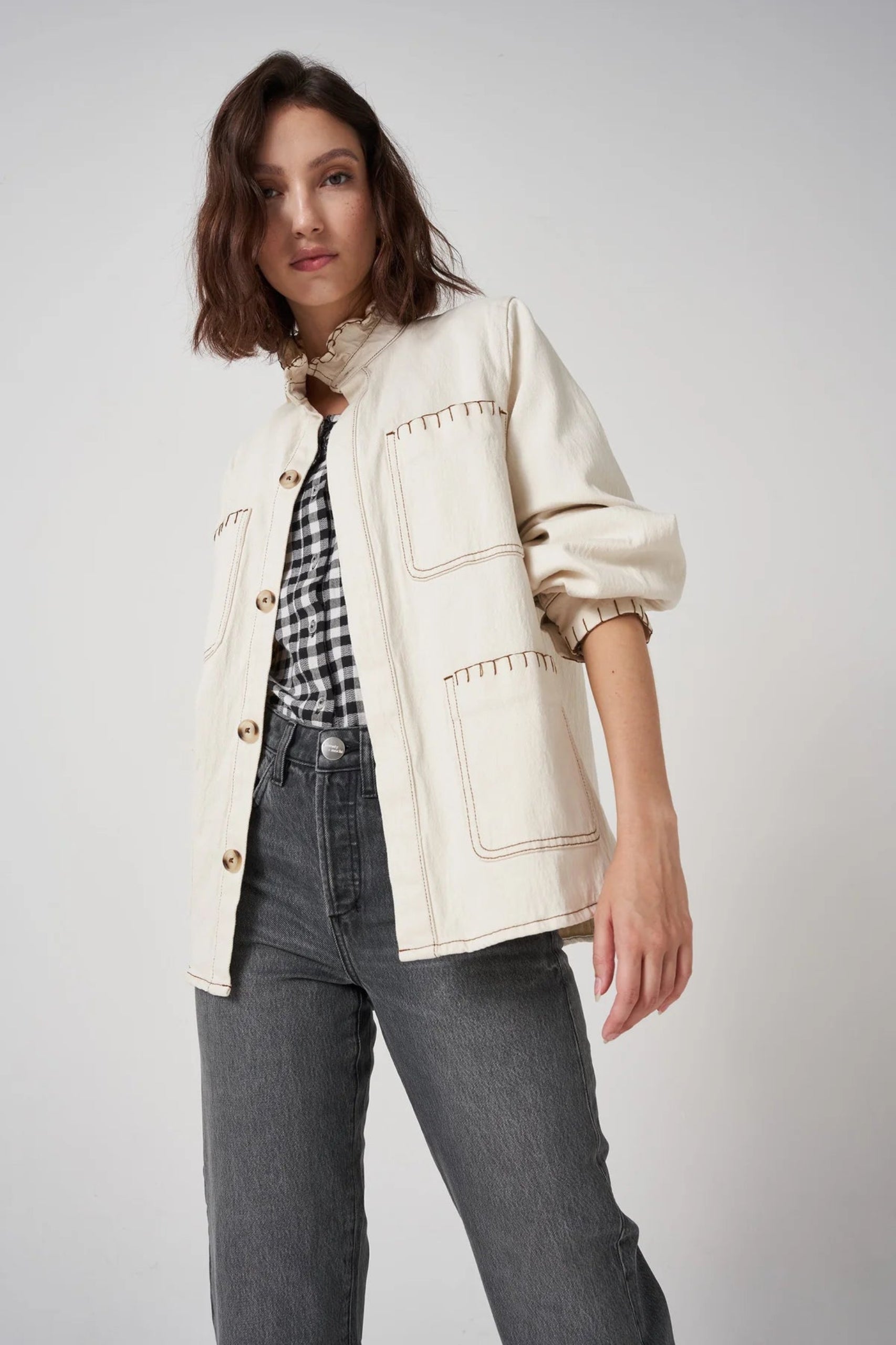 woman wearing a cream denim jacket with sleeve pushed up and buttons open