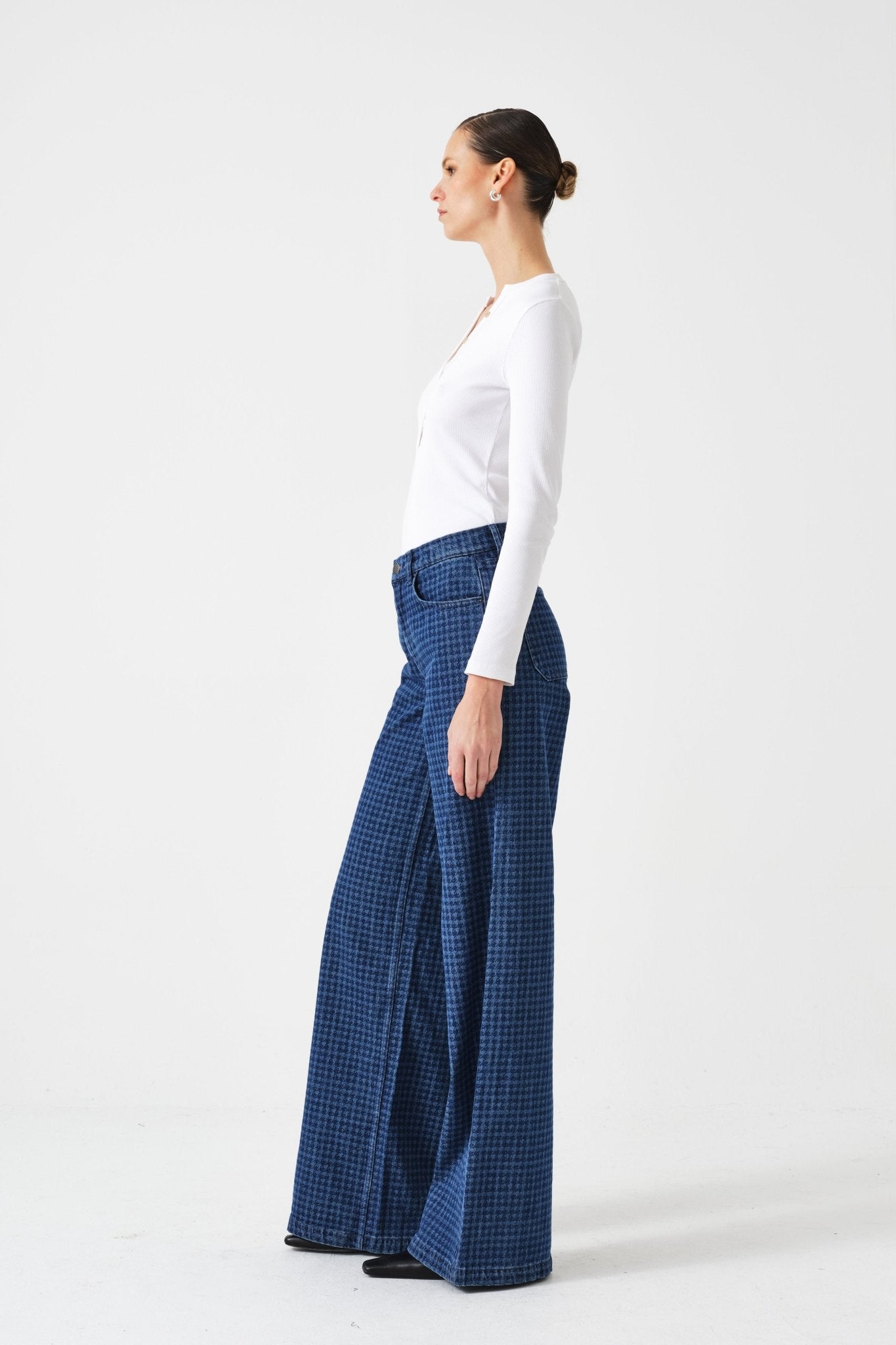 Side view of a woman wearing a white top and blue checkered pants