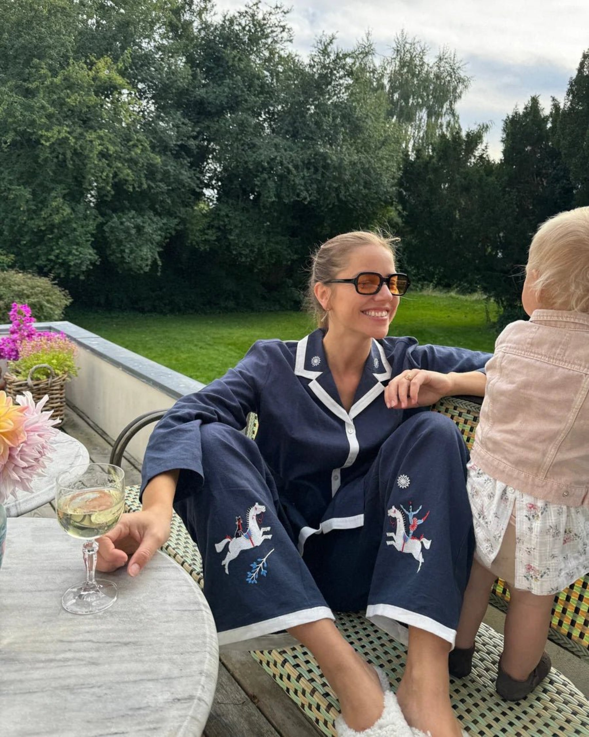 Woman in navy blue and white trim long sleeve pyjama set and a baby outside at table - ANNIE.G