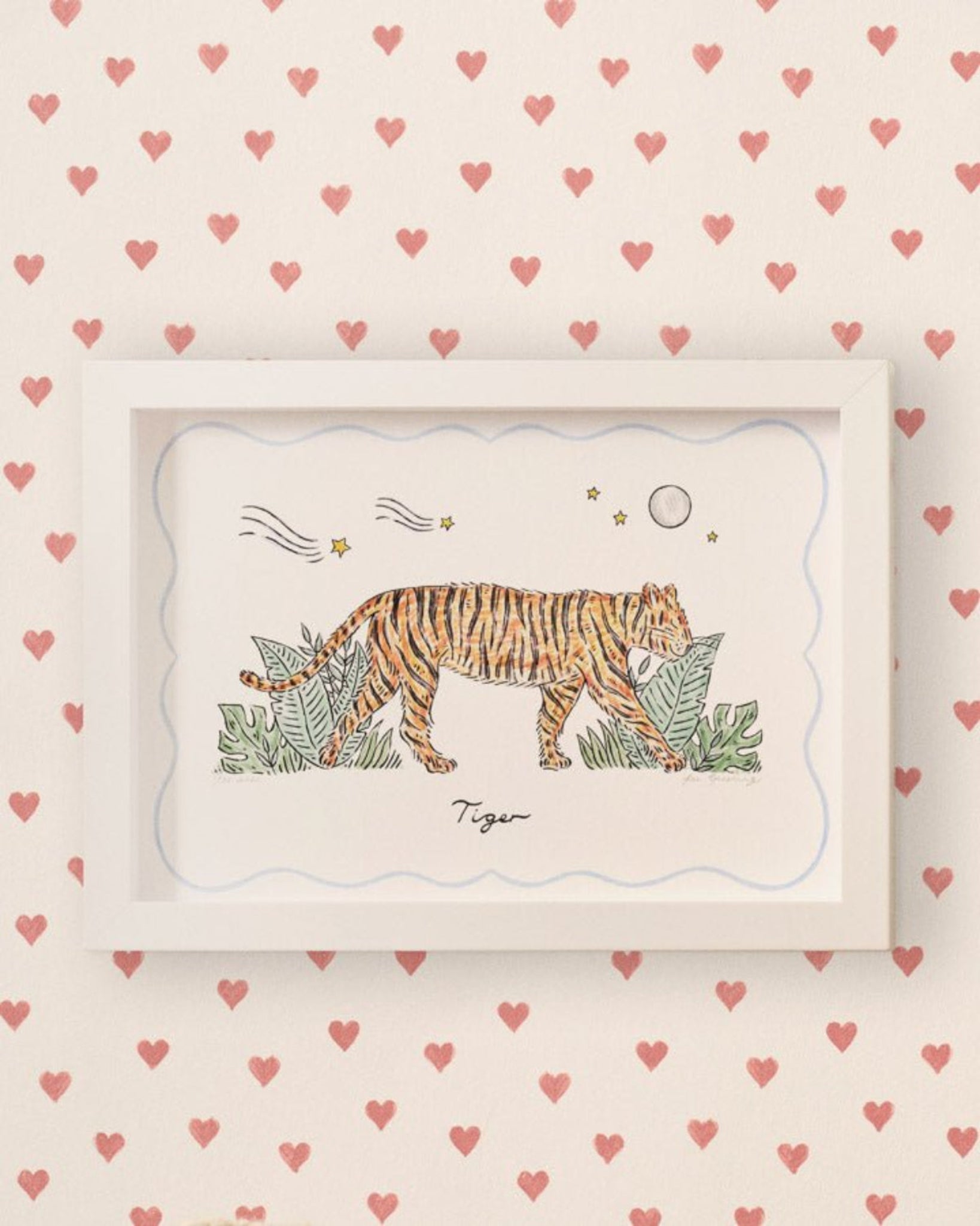 A framed Tiger Print hanging on a wall in a white frame with red heart wallpaper on the wall - ANNIE.G