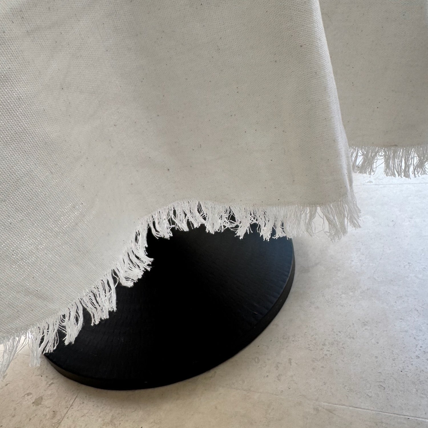 Round pedestal table with white frayed edge tablecloth
