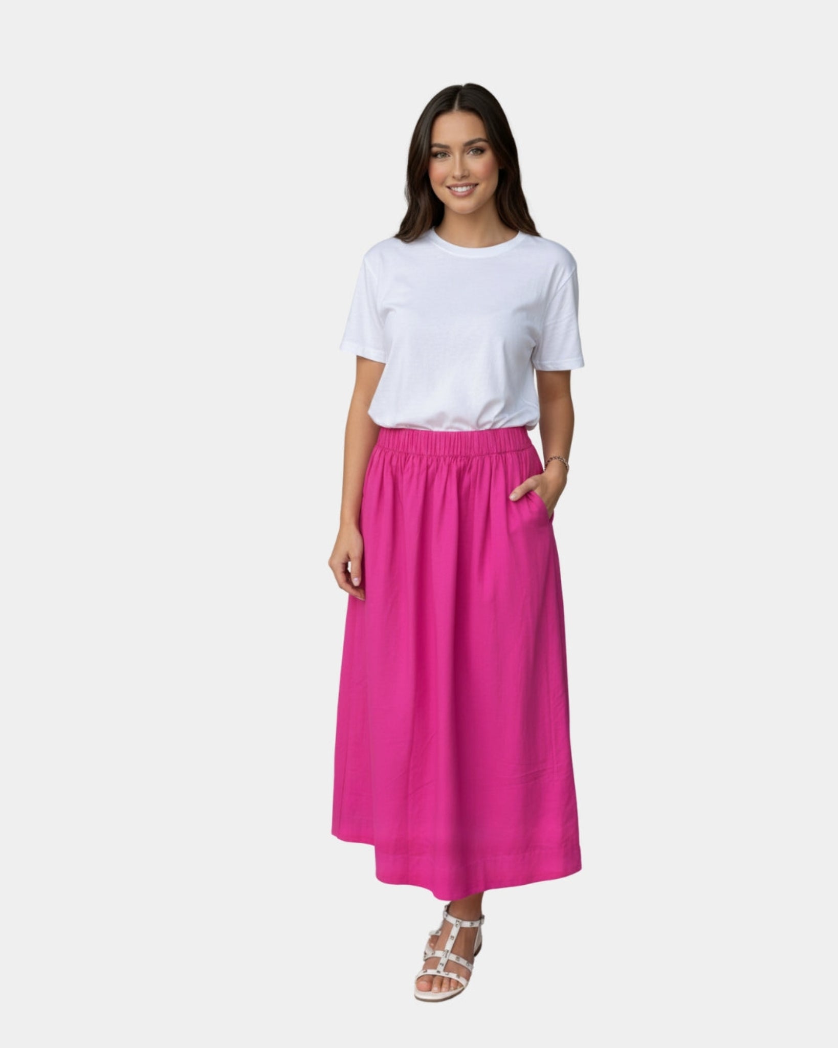 Woman wearing a white t-shirt and hot pink skirt and sandles.