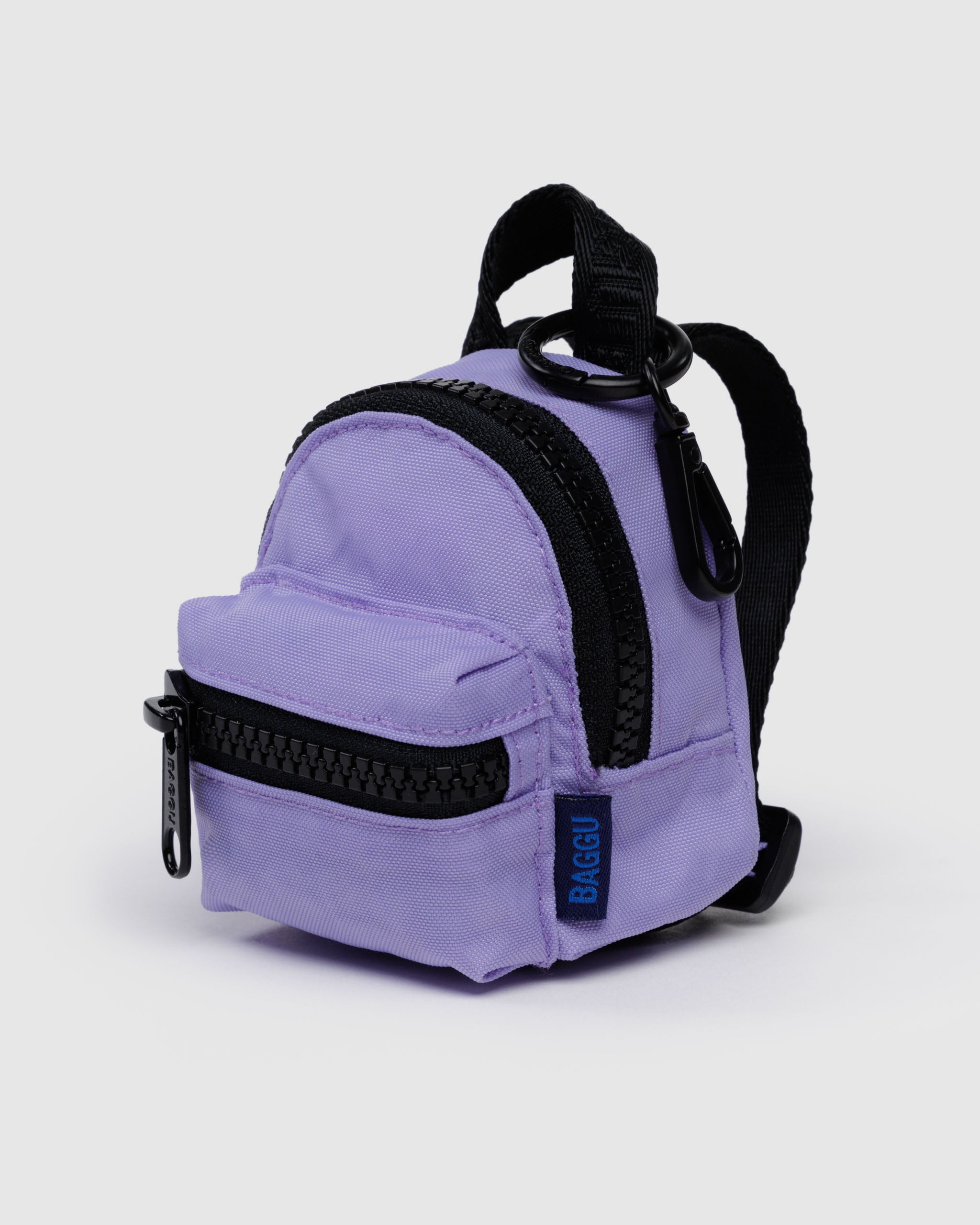 Small purple backpack bag charm with black straps and two black zippered pockets.