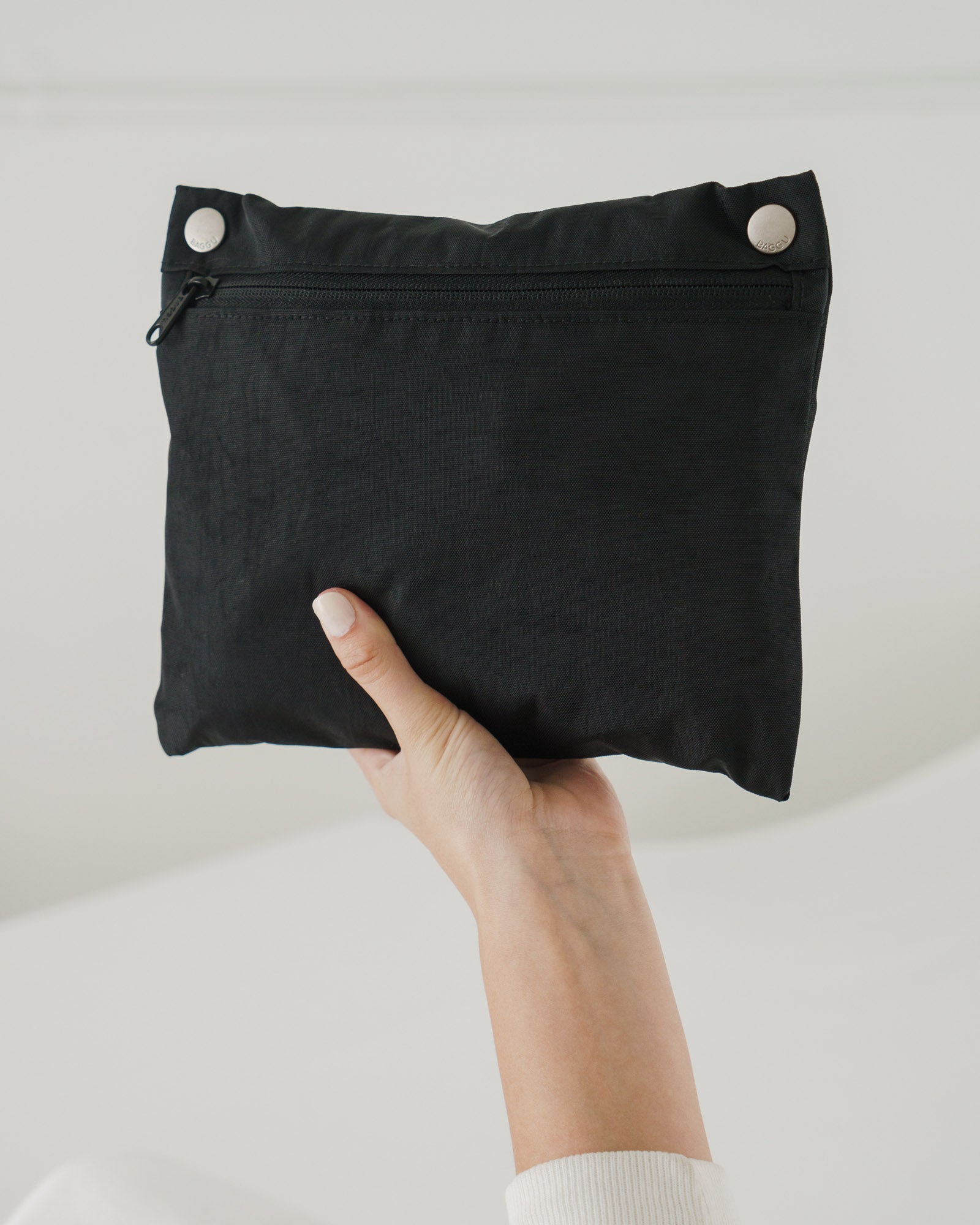 Hand holding the detachable black pouch of black cloud bag folded inside - ANNIE.G