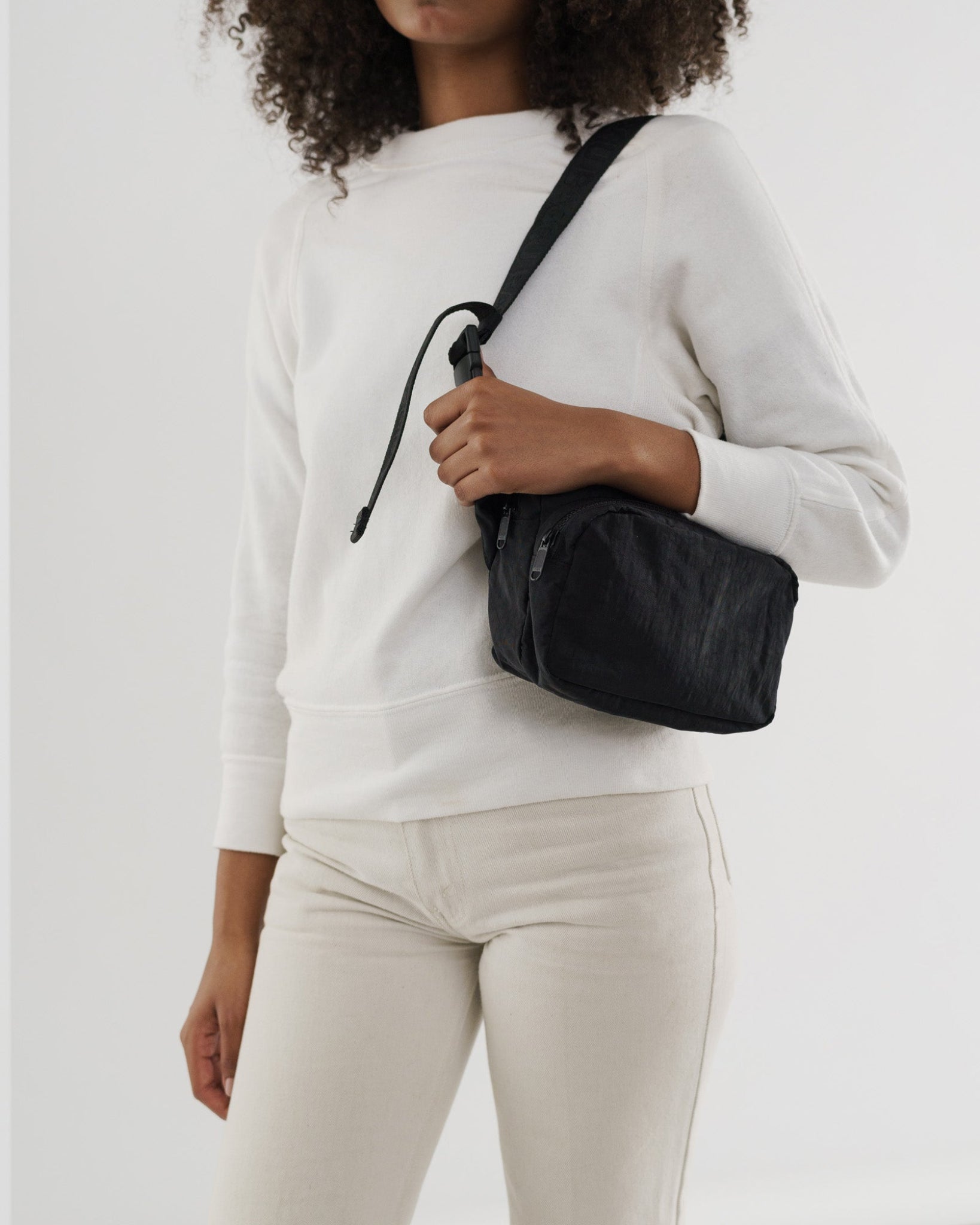 Person wearing a black fanny pack on shoulder.