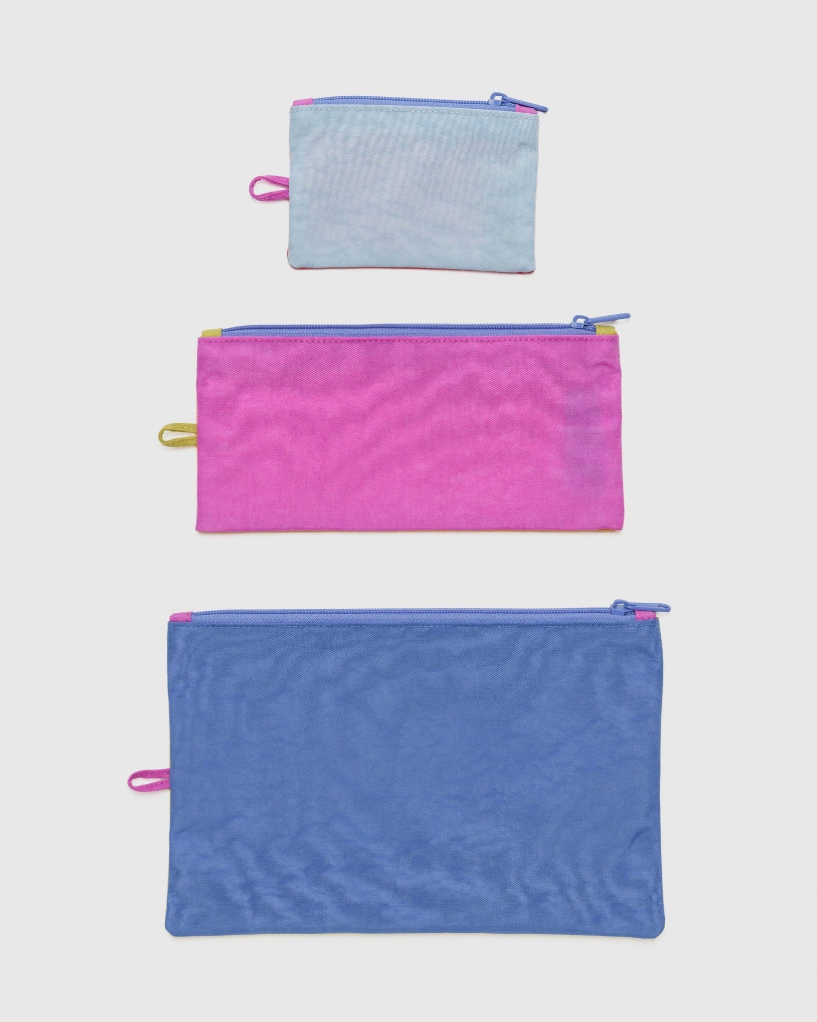 Set of 3 different sized and coloured zipper flat pouches lying flat.