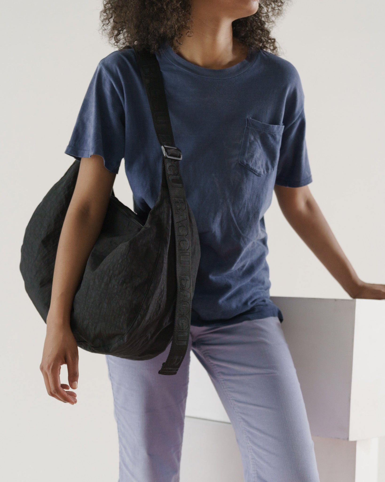 Woman wearing Baggu black Large Nylon Crescent Bag on shoulder with adjustable strap- ANNIE.G